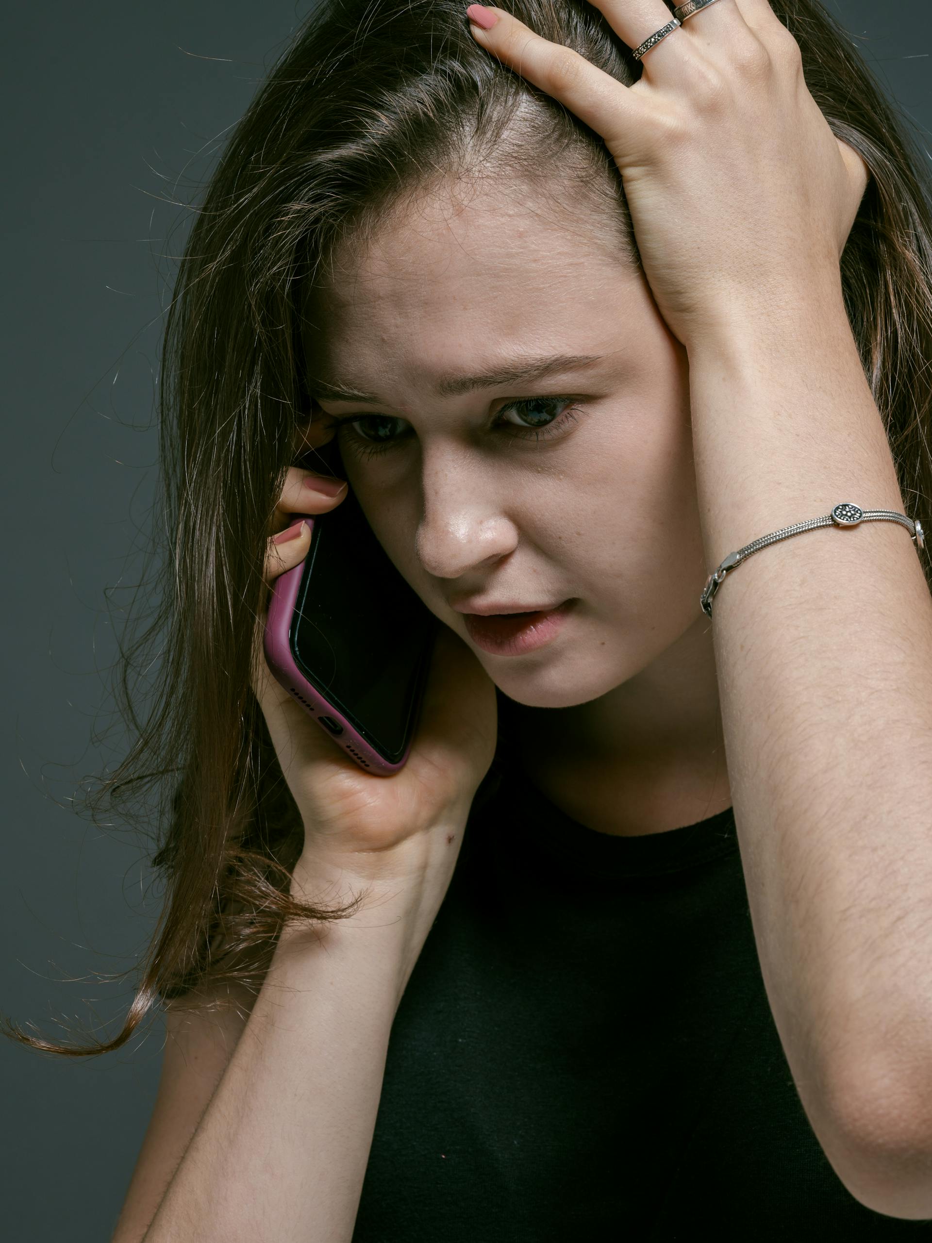 Una mujer hablando por el móvil con la mano en la cabeza | Fuente: Pexels