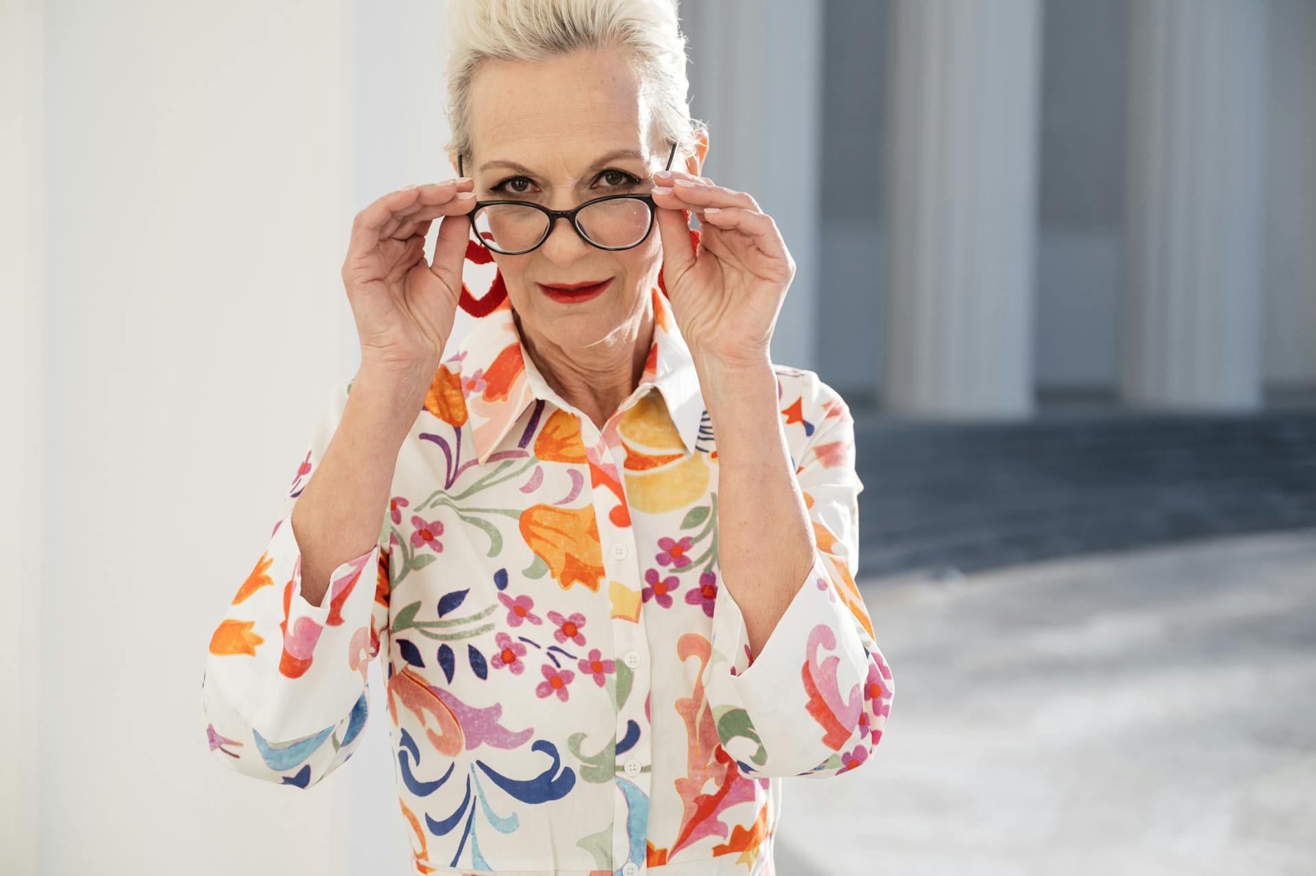 Una mujer mayor sujetando sus gafas | Fuente: Pexels