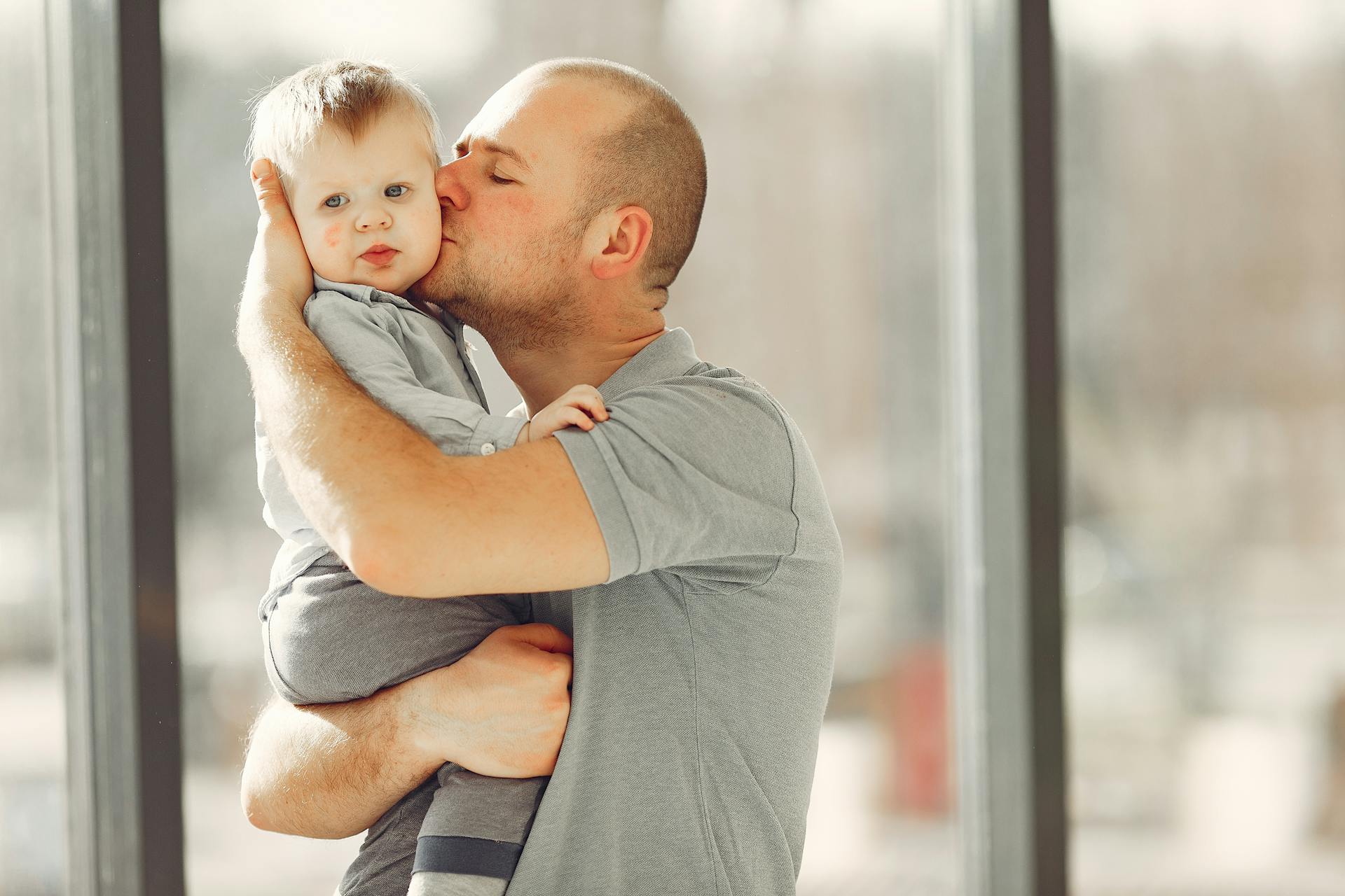 Un hombre llevando y besando a su hijo | Fuente: Pexels