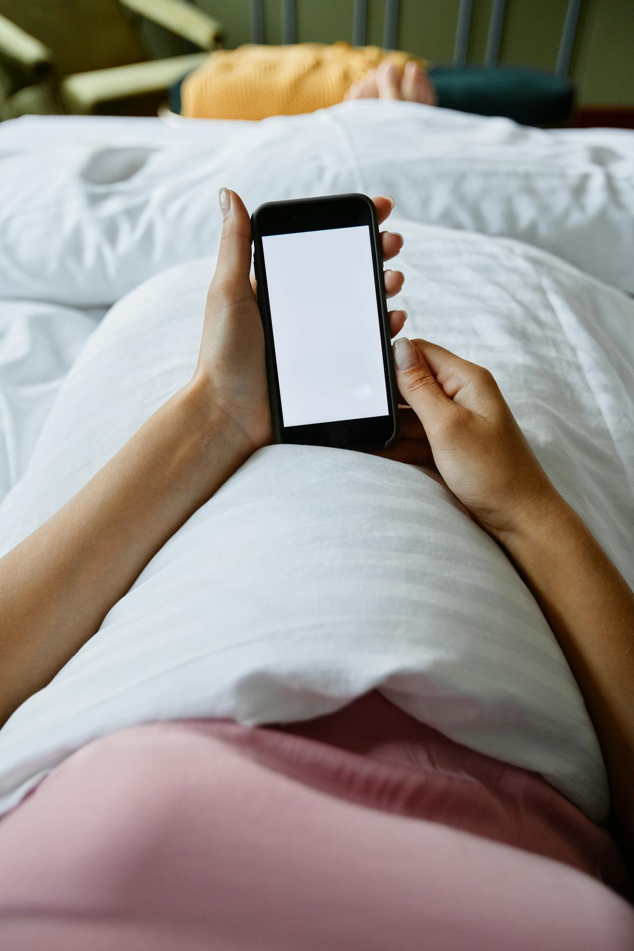Una mujer usando su teléfono en la cama | Fuente: Pexels