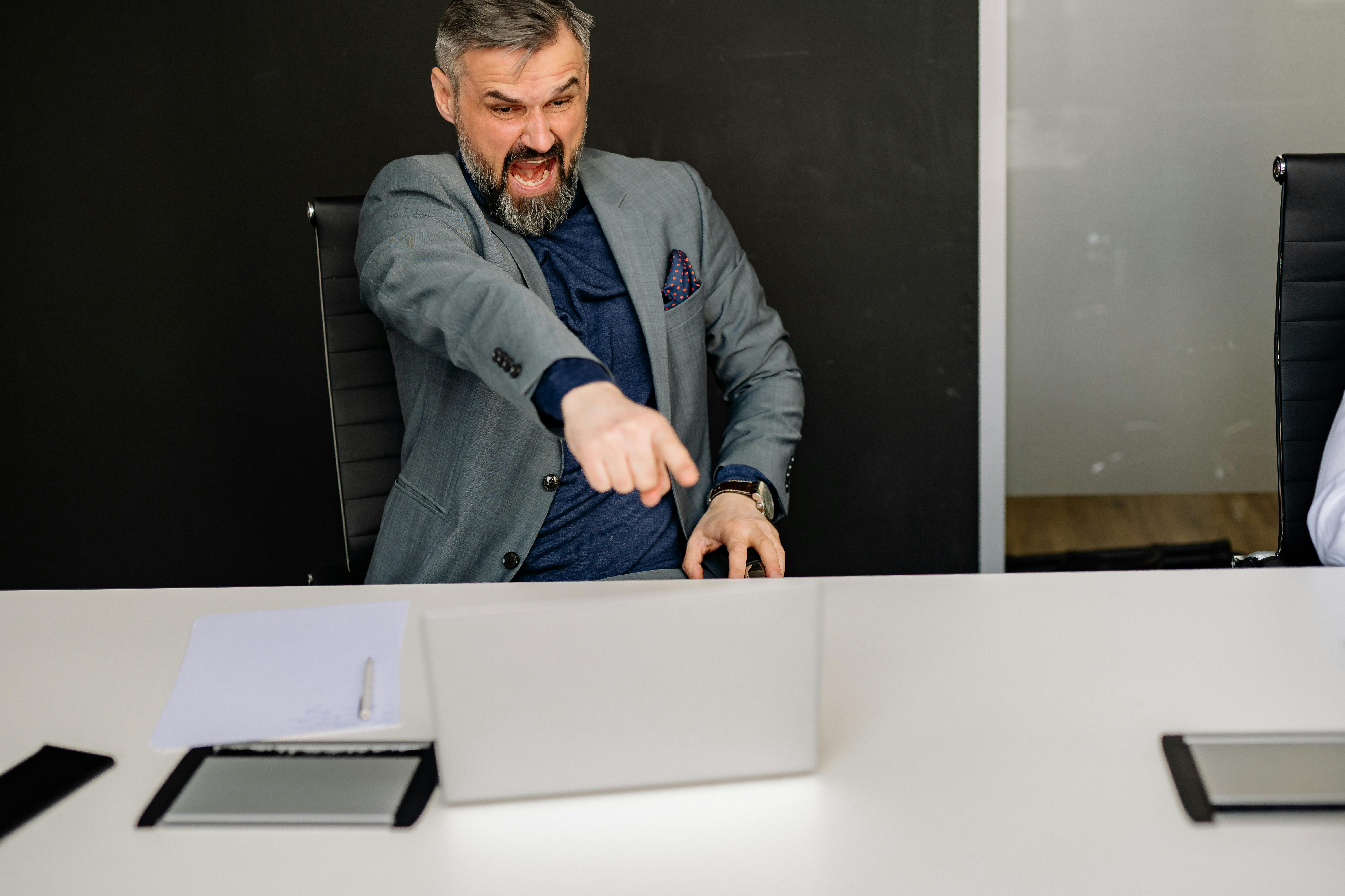 Un hombre de negocios enfadado señalando la pantalla de su portátil | Fuente: Pexels