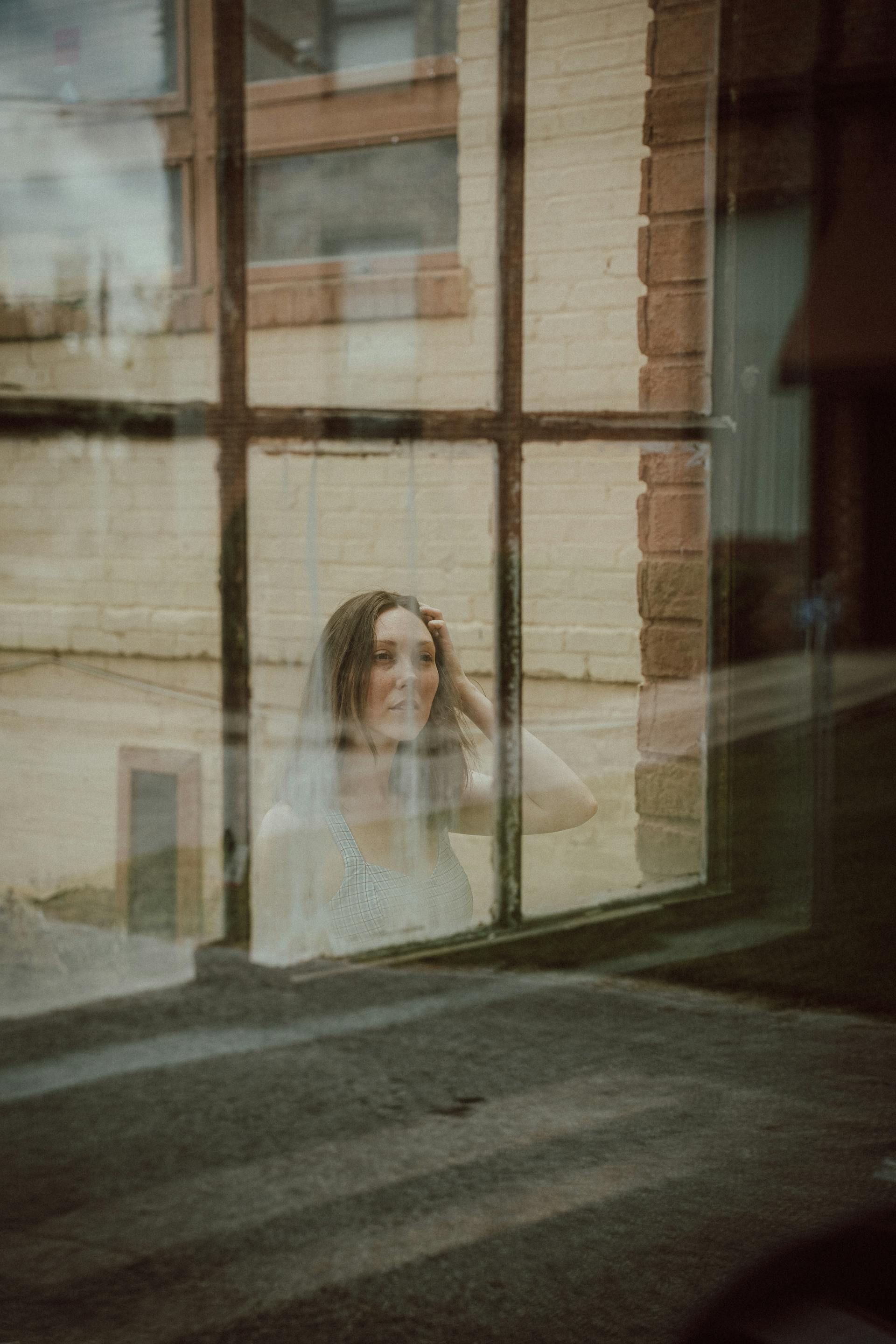 Una mujer mirando por la ventana de un edificio | Fuente: Pexels