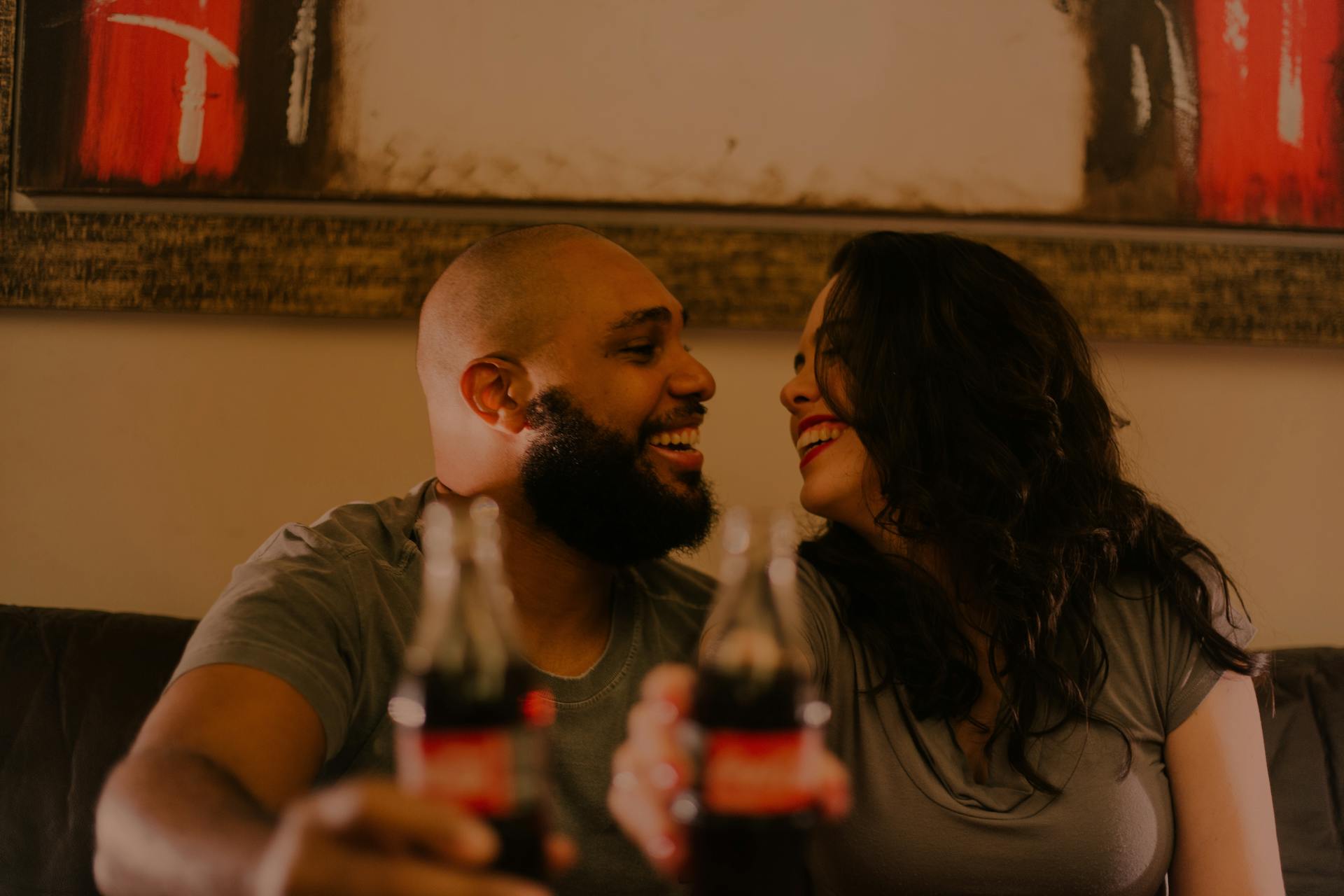 Una pareja ríe mientras sostiene sus botellas de refresco | Fuente: Pexels