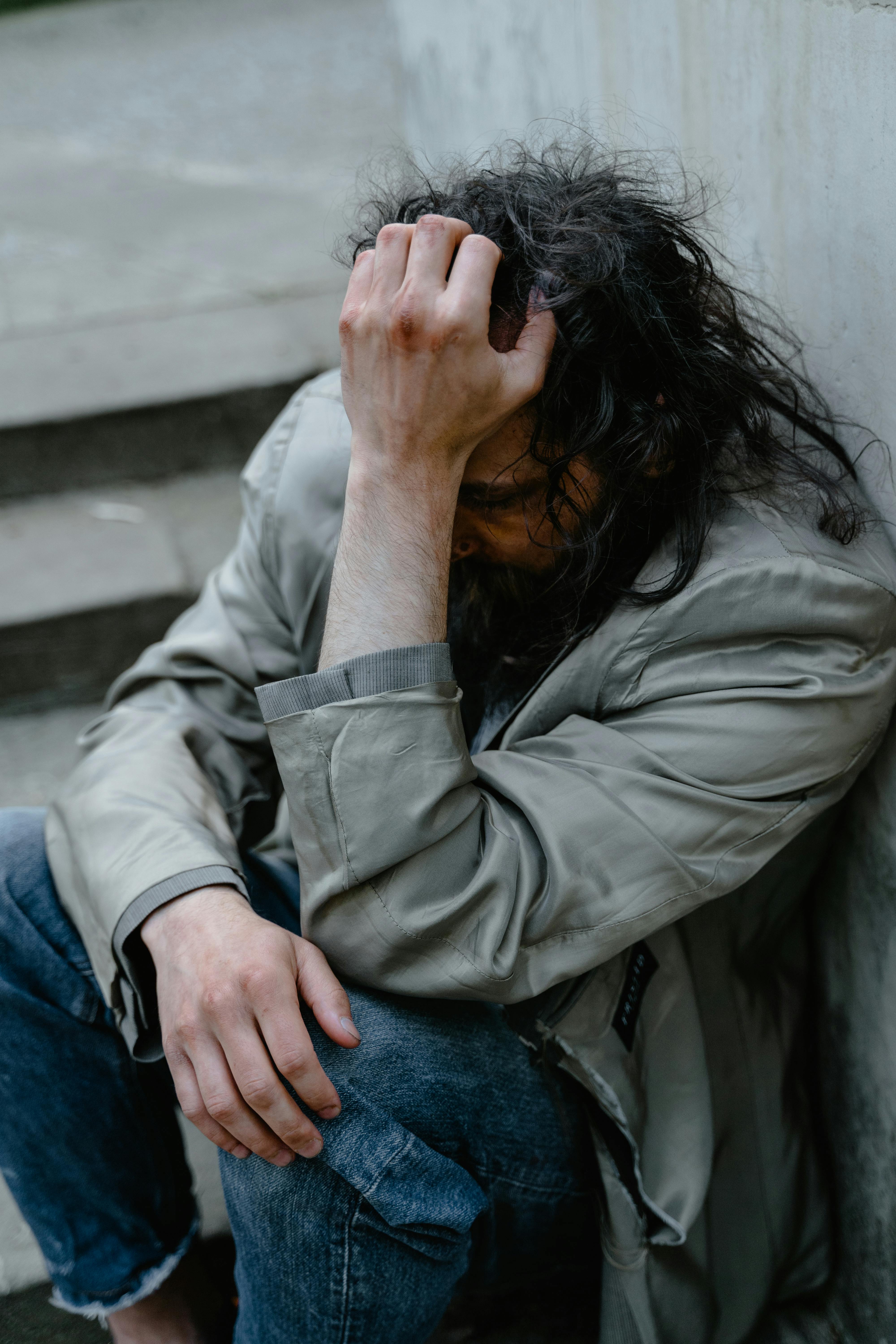 Un hombre miserable sentado contra una pared | Fuente: Pexels