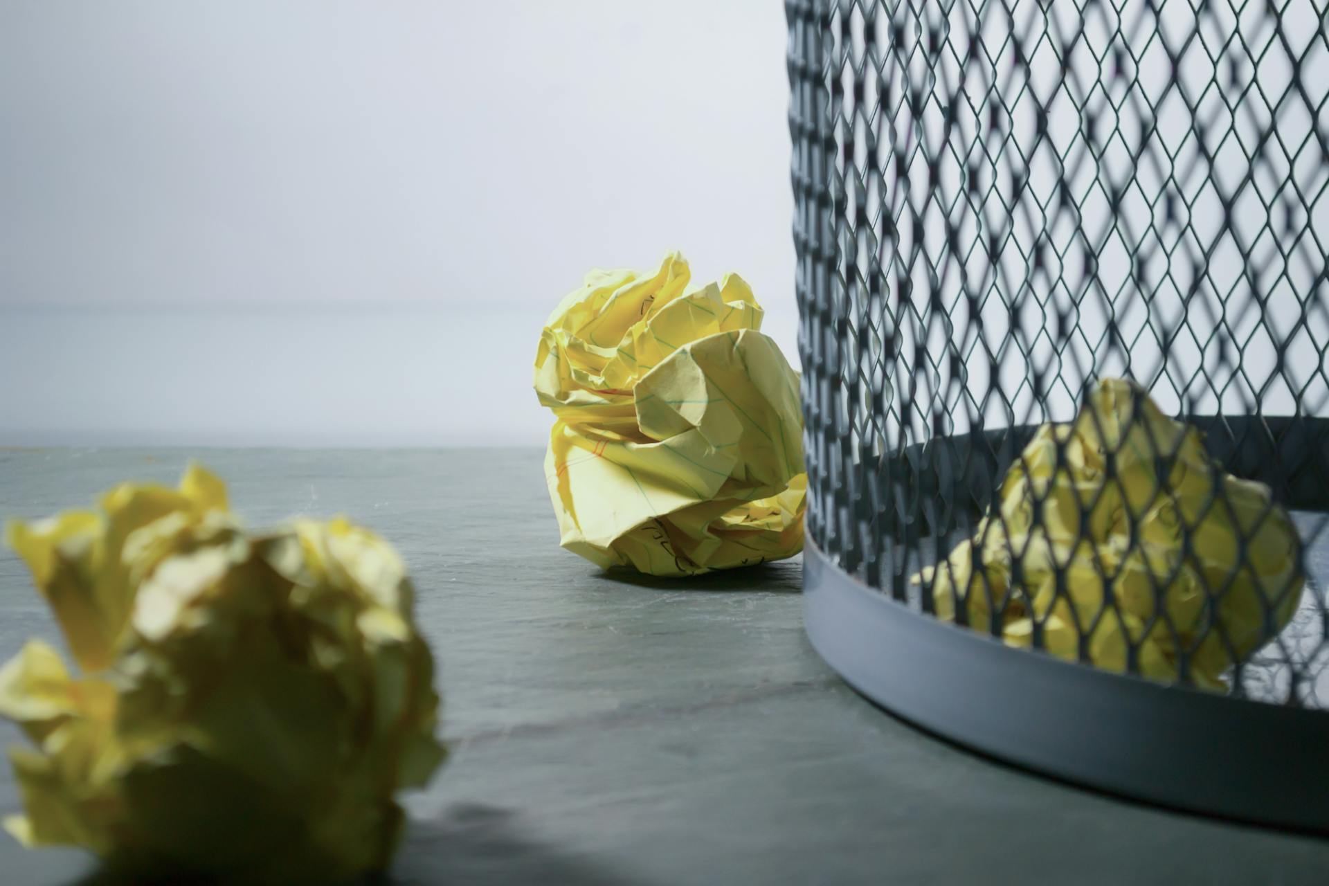 Papel arrugado cerca del cubo de la basura | Fuente: Pexels