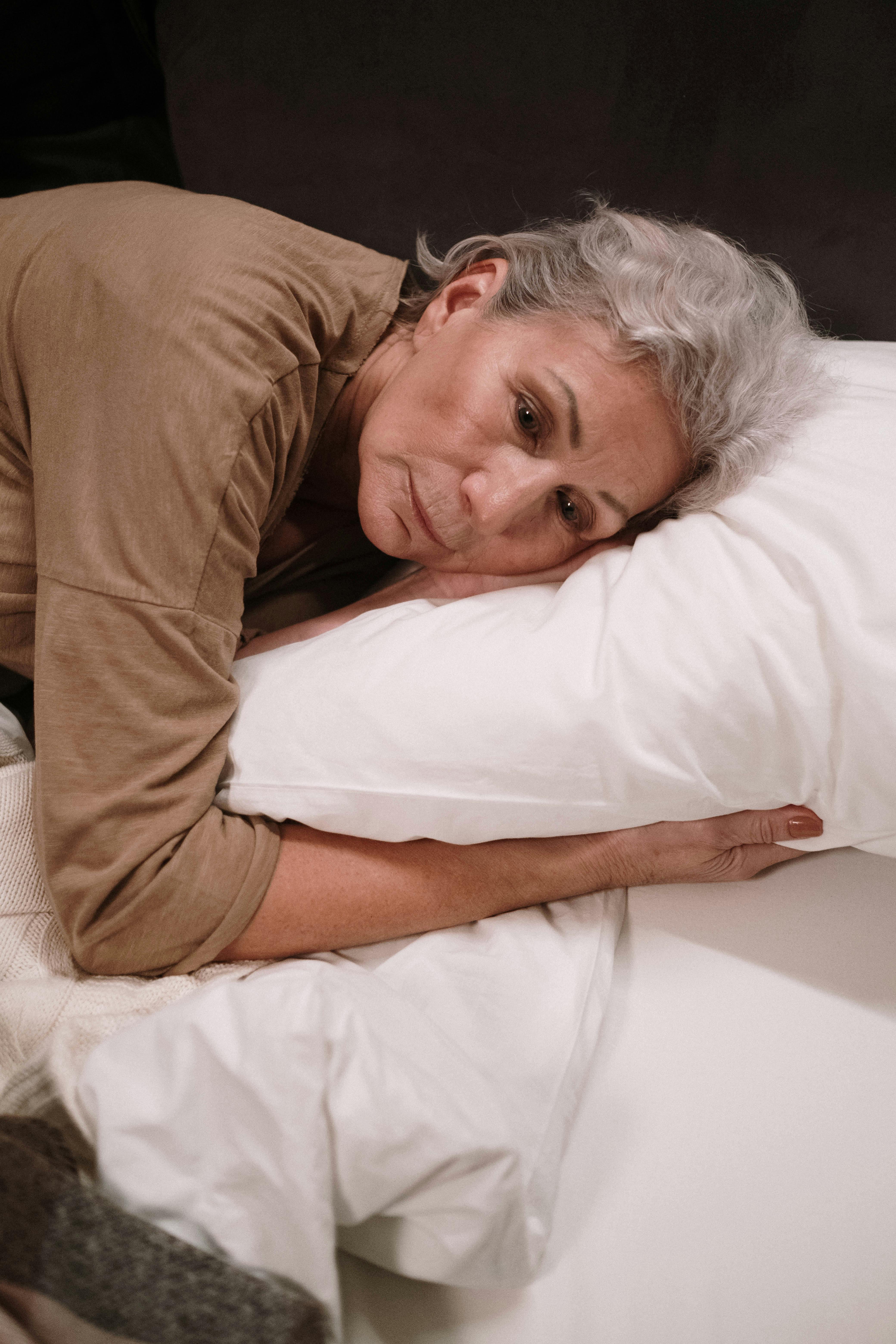 Una mujer triste tumbada en la cama | Fuente: Pexels