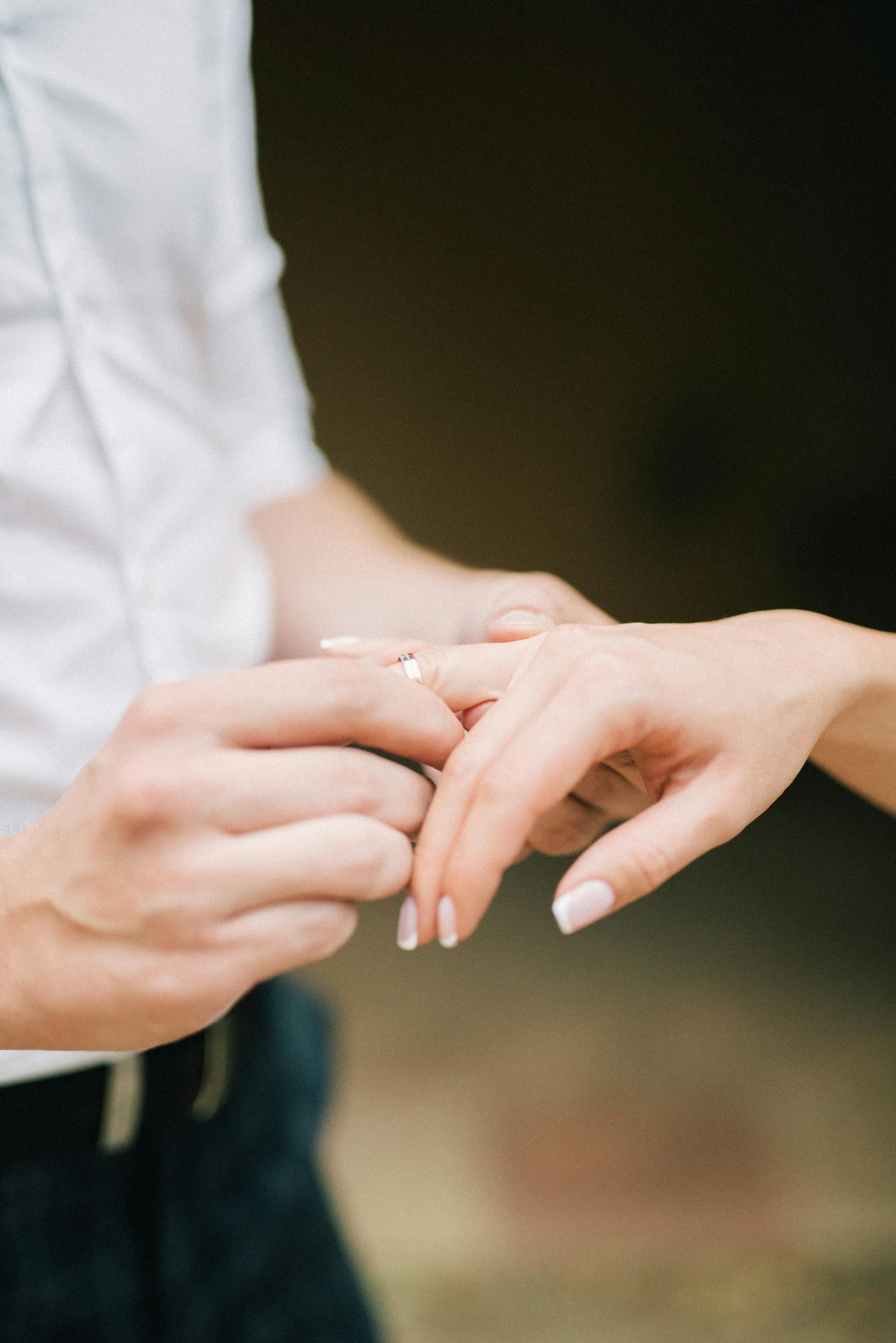 Un hombre deslizando un anillo en el dedo de una mujer | Fuente: Pexels