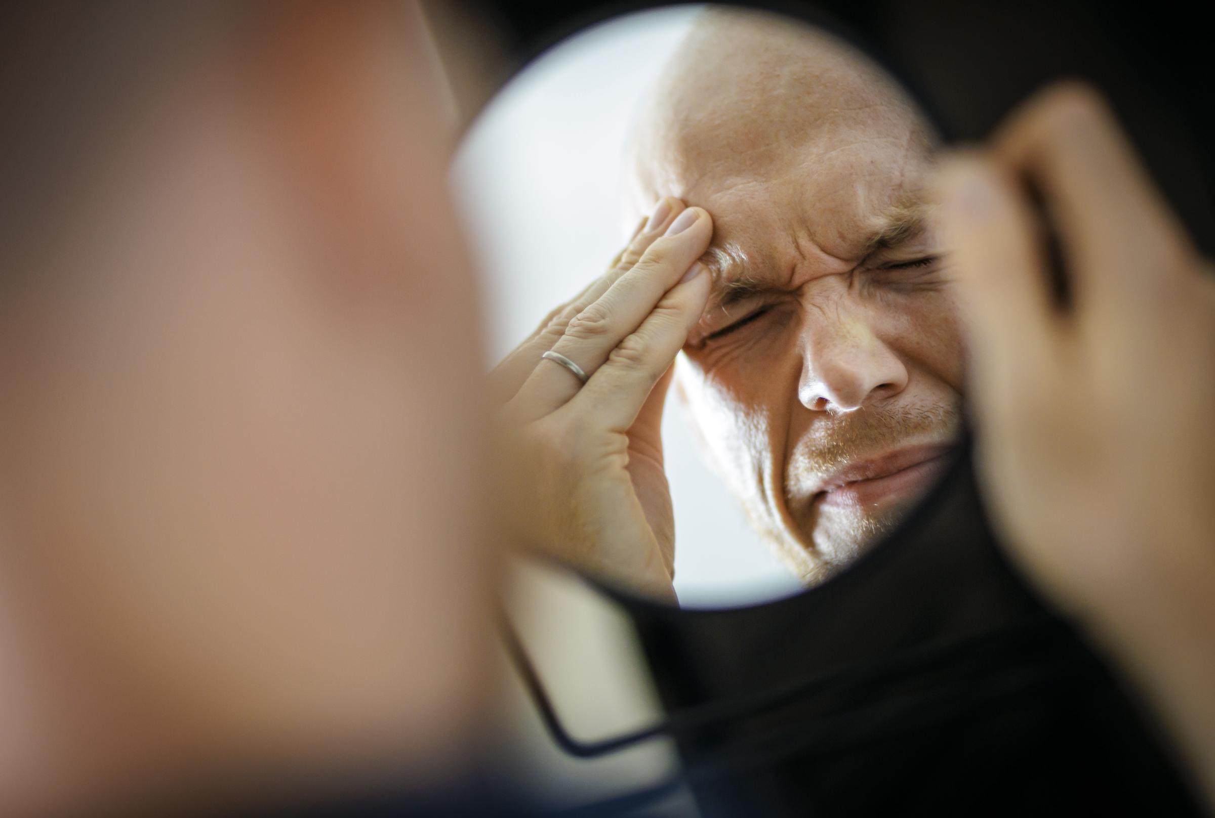 Imagen simbólica que representa las migrañas y los dolores de cabeza: hombre sujetándose la cabeza dolorida por la incomodidad | Fuente: Getty Images