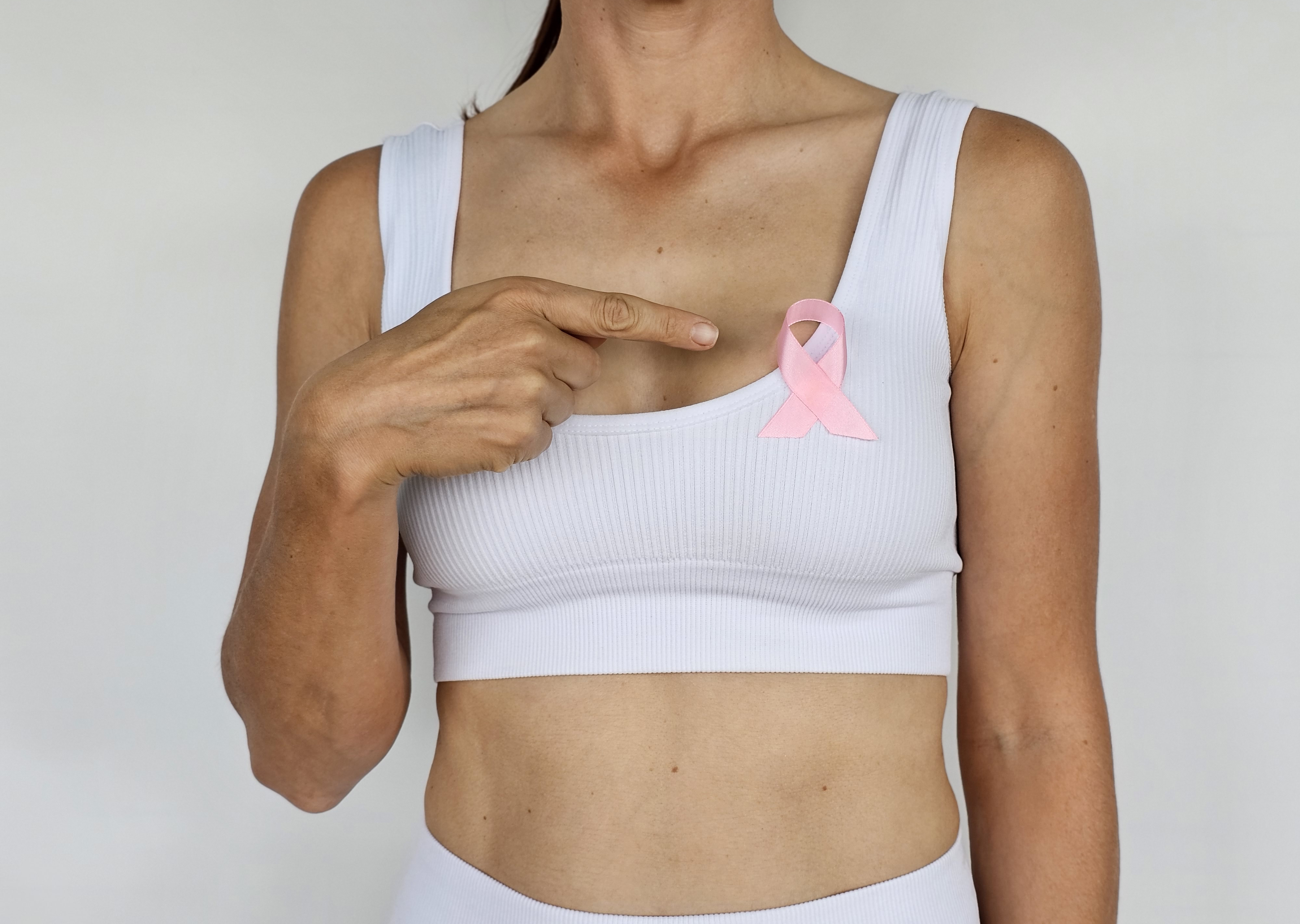 Una mujer señala un lazo rosa prendido en el pecho, símbolo de la concienciación sobre el cáncer de mama | Fuente: Getty Images