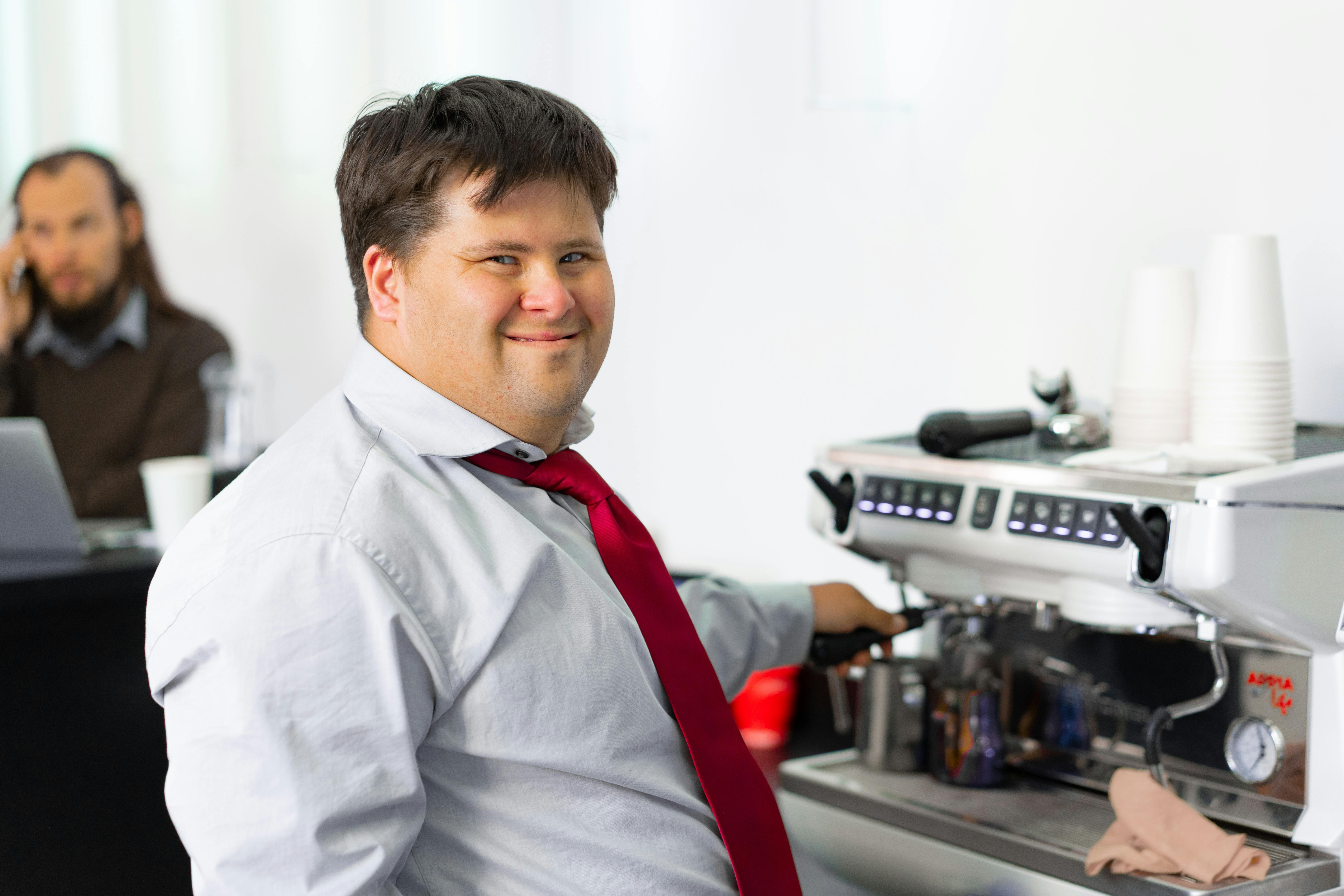 Un hombre sonriendo ante una máquina de café | Fuente: Pexels
