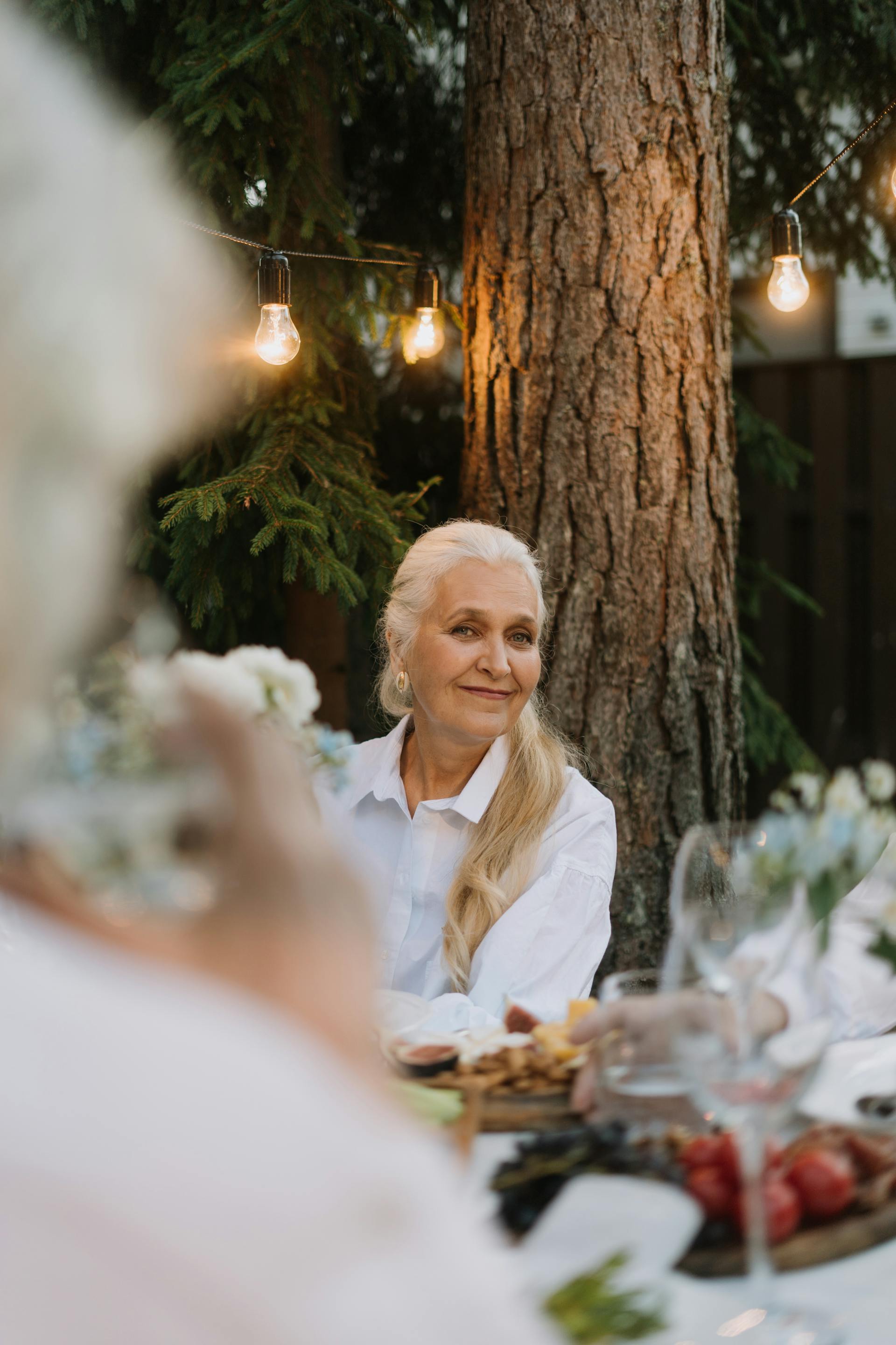 Una mujer madura con el pelo largo y rubio sonriendo en una fiesta | Fuente: Pexels