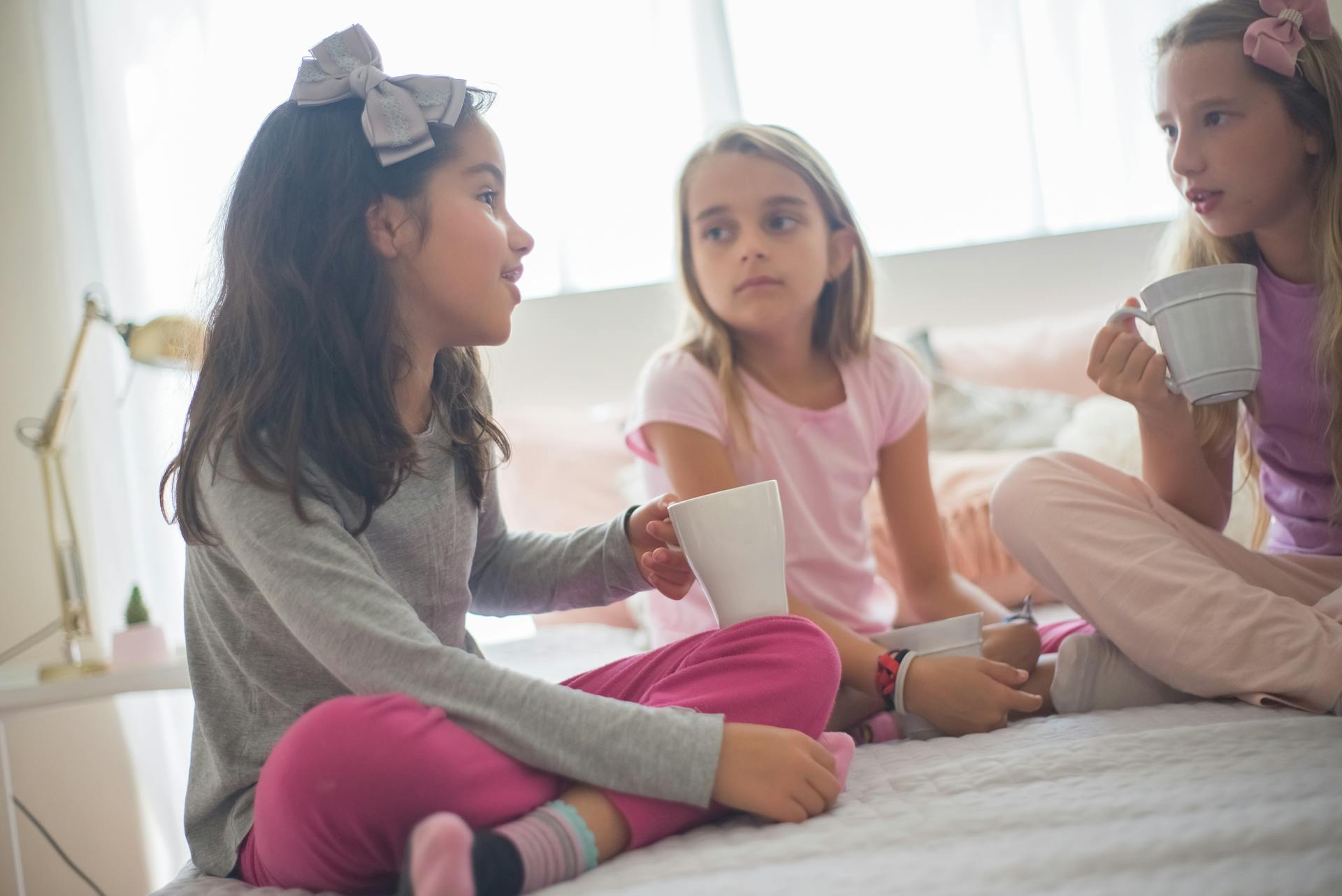 Tres chicas sosteniendo tazas mientras hablan | Fuente: Pexels