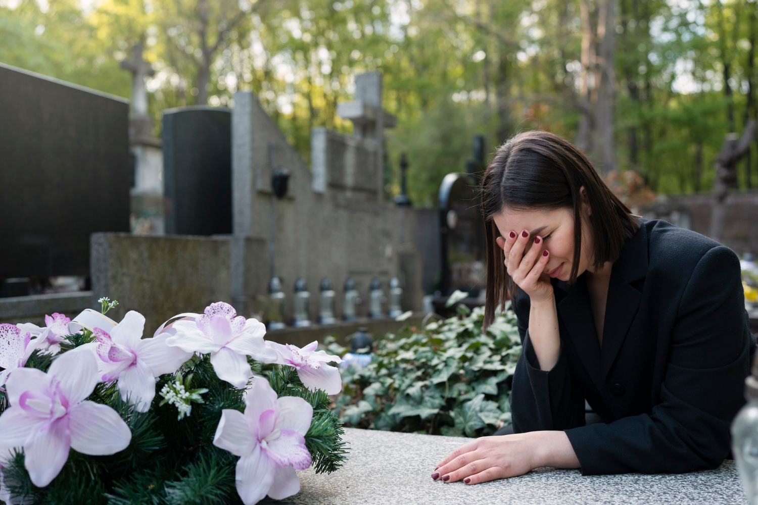 Una mujer de luto junto a una tumba en un cementerio | Fuente: Freepik