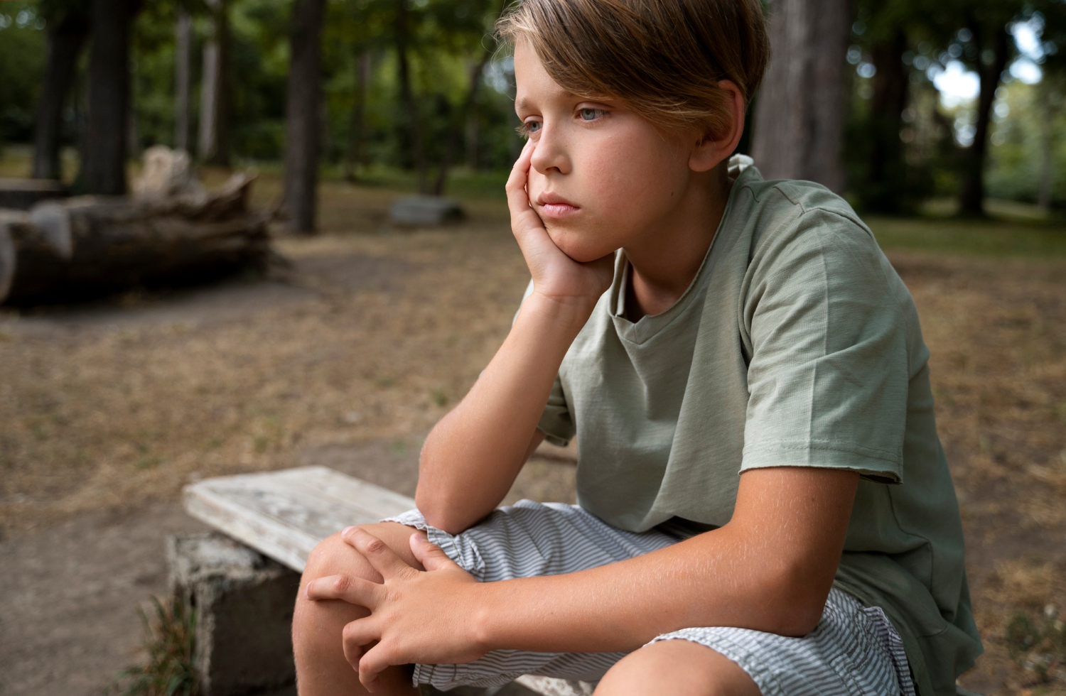 Un niño pensativo sentado en un banco | Fuente: Freepik