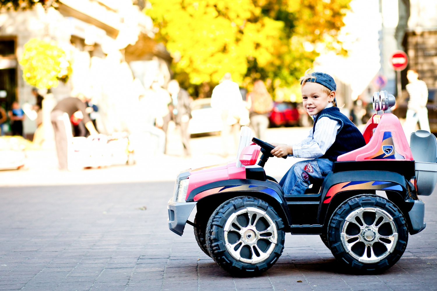 Un niño feliz montado en su auto de juguete | Fuente: Freepik