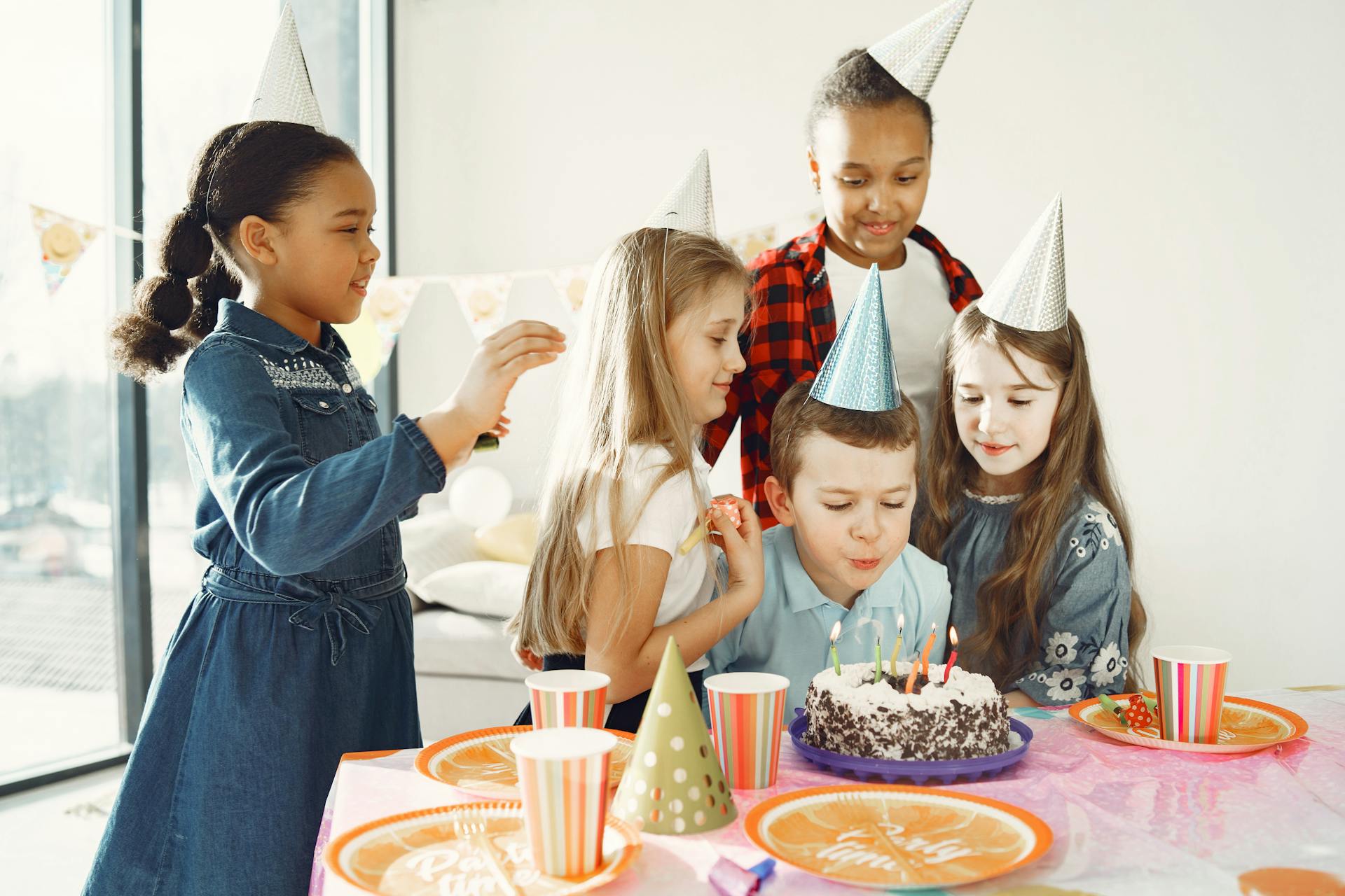 Un niño sopla las velas de su pastel de cumpleaños mientras unos niños encantados lo rodean | Fuente: Pexels