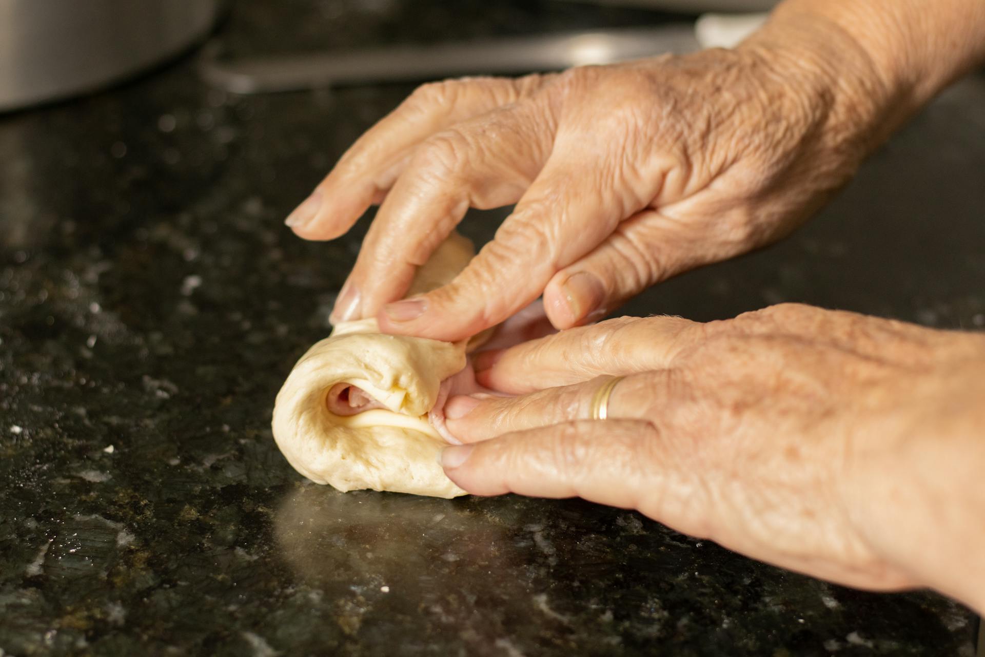 Primer plano de las manos de una mujer doblando un trozo de masa blanda | Fuente: Pexels