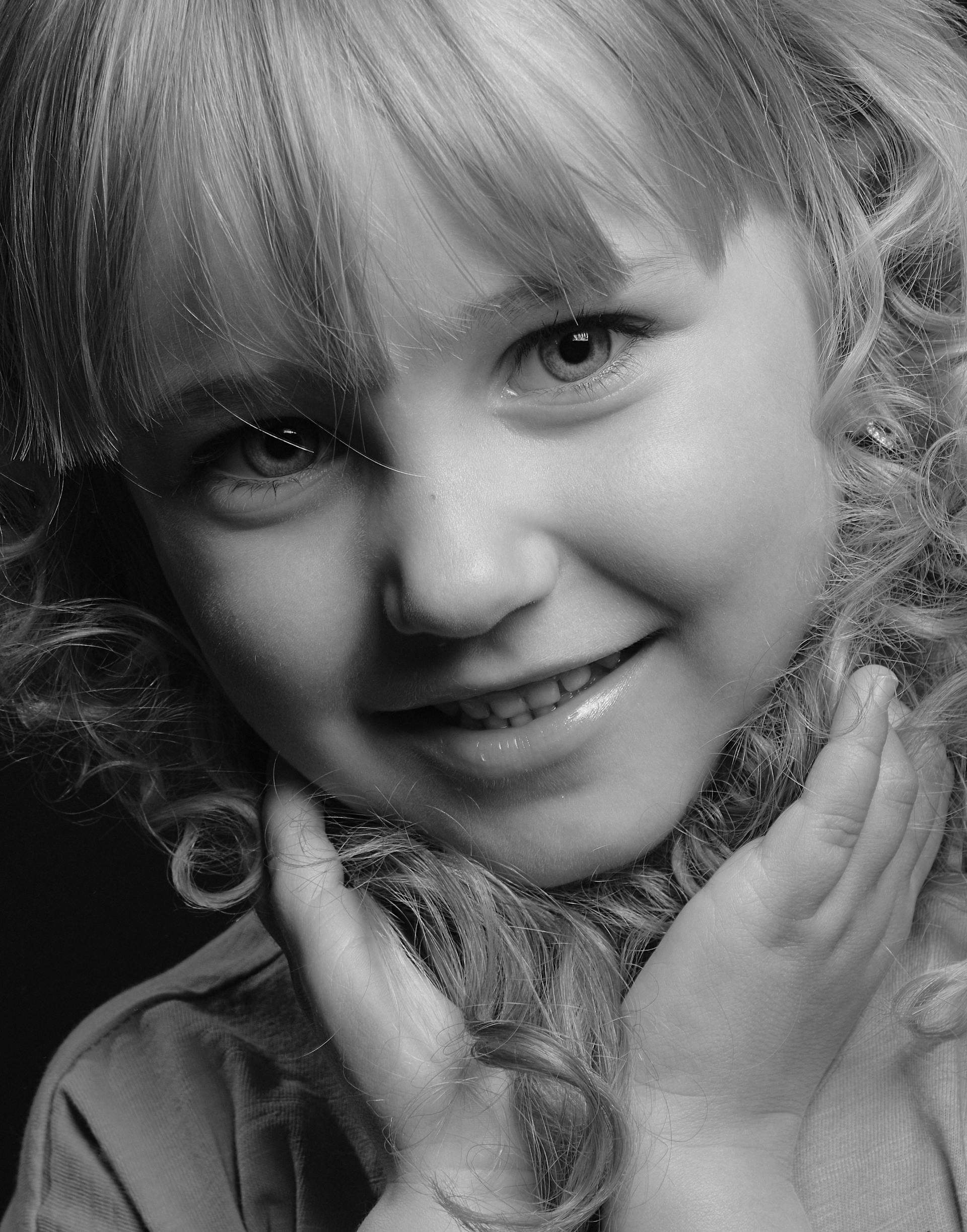 Foto en escala de grises de una niña sonriente | Fuente: Pexels