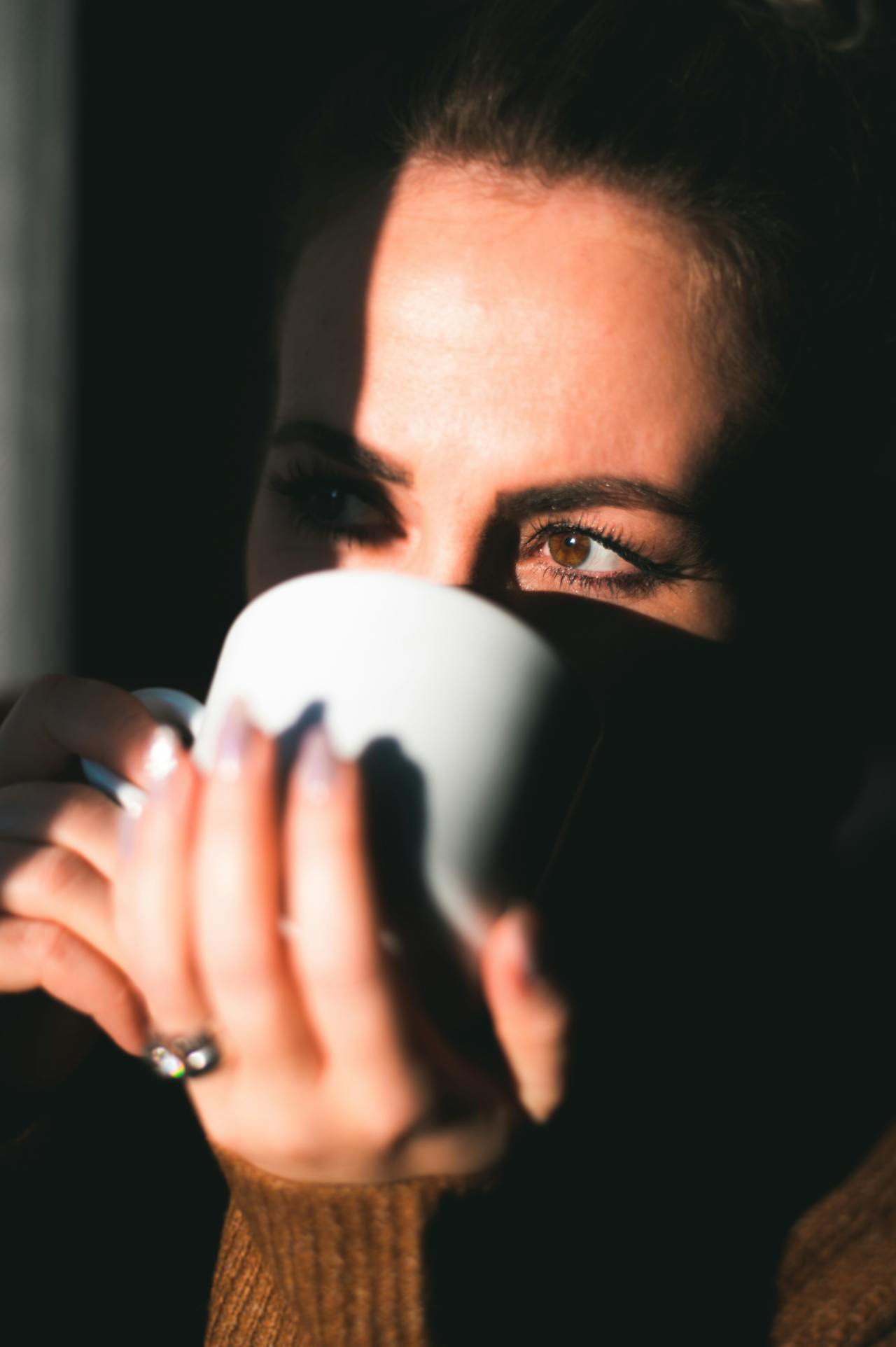 Una mujer bebiendo una bebida de una taza de cerámica blanca | Fuente: Pexels