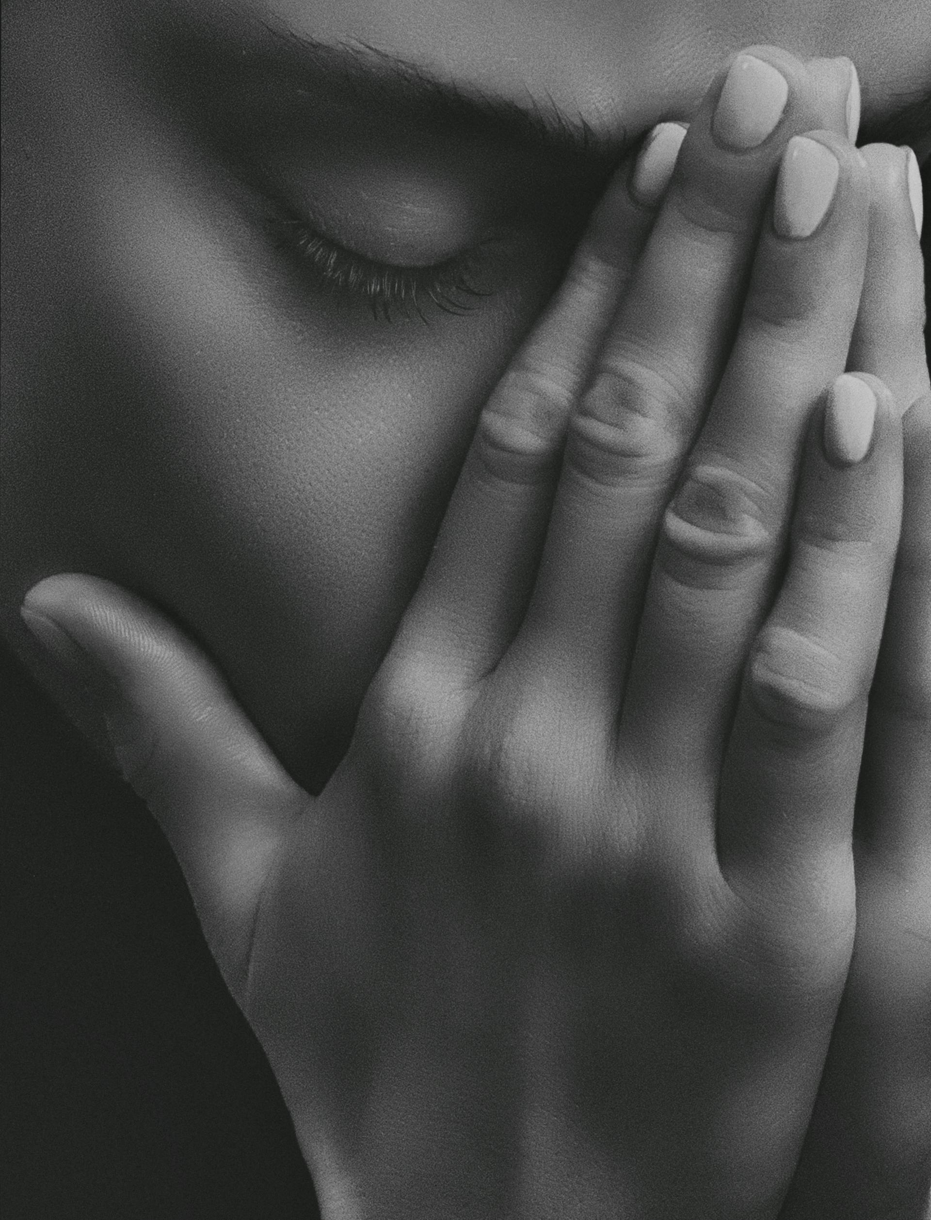 Foto en escala de grises de una mujer cubriéndose la cara con las manos | Fuente: Pexels