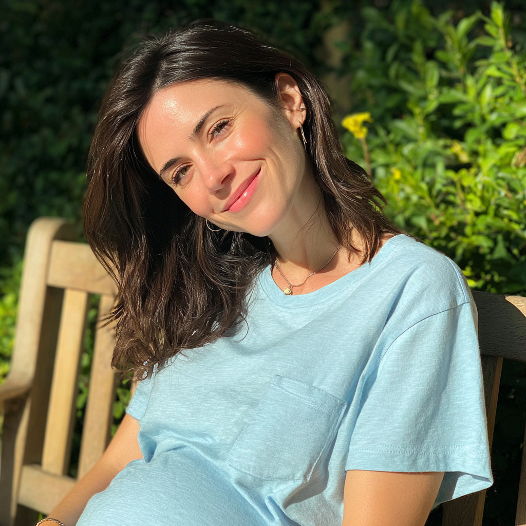 Una mujer embarazada sonriente sentada al aire libre | Fuente: Midjourney