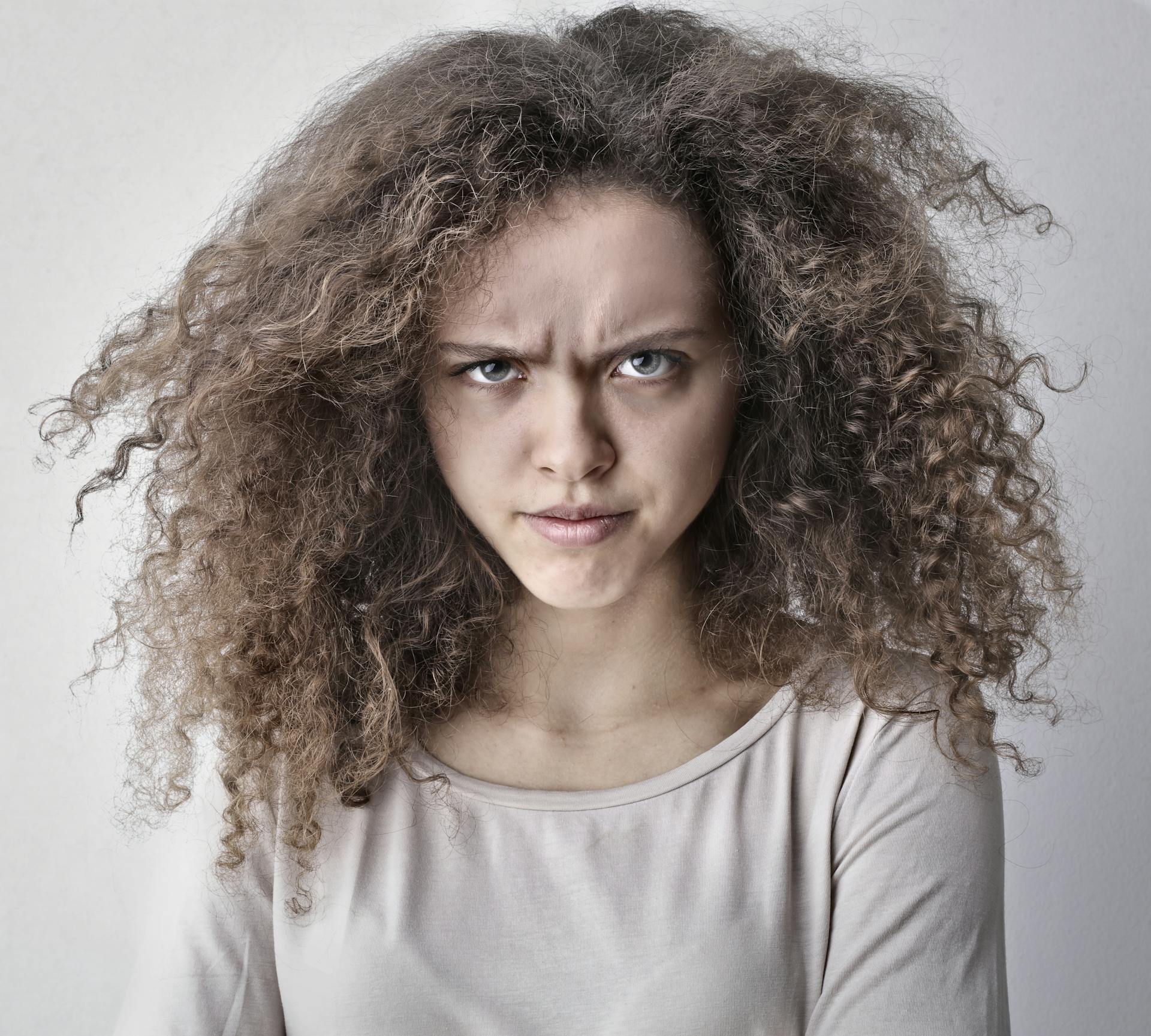 Una joven de pelo rizado frunciendo las cejas | Fuente: Pexels
