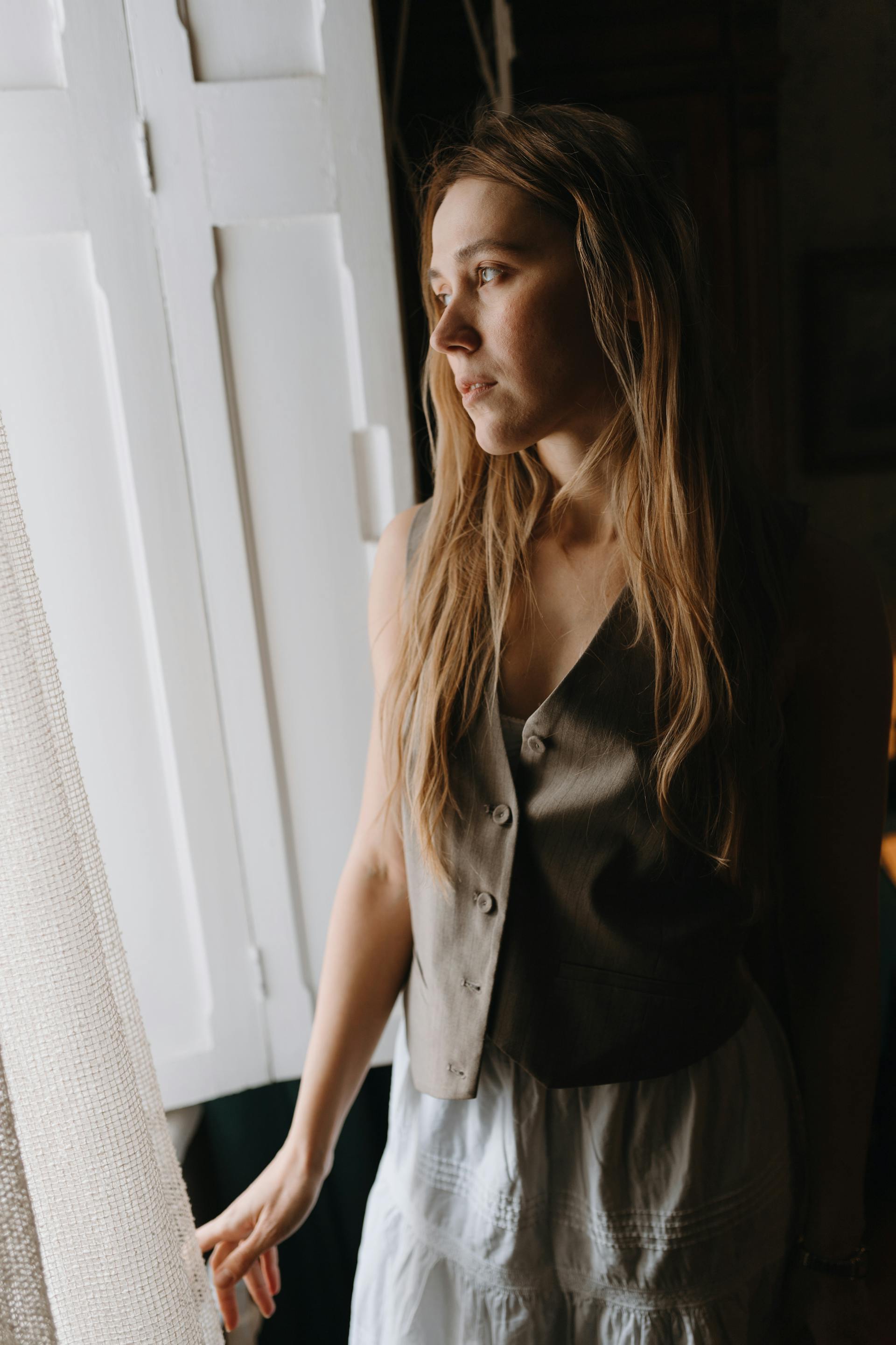 Una mujer junto a la ventana de una habitación | Fuente: Pexels