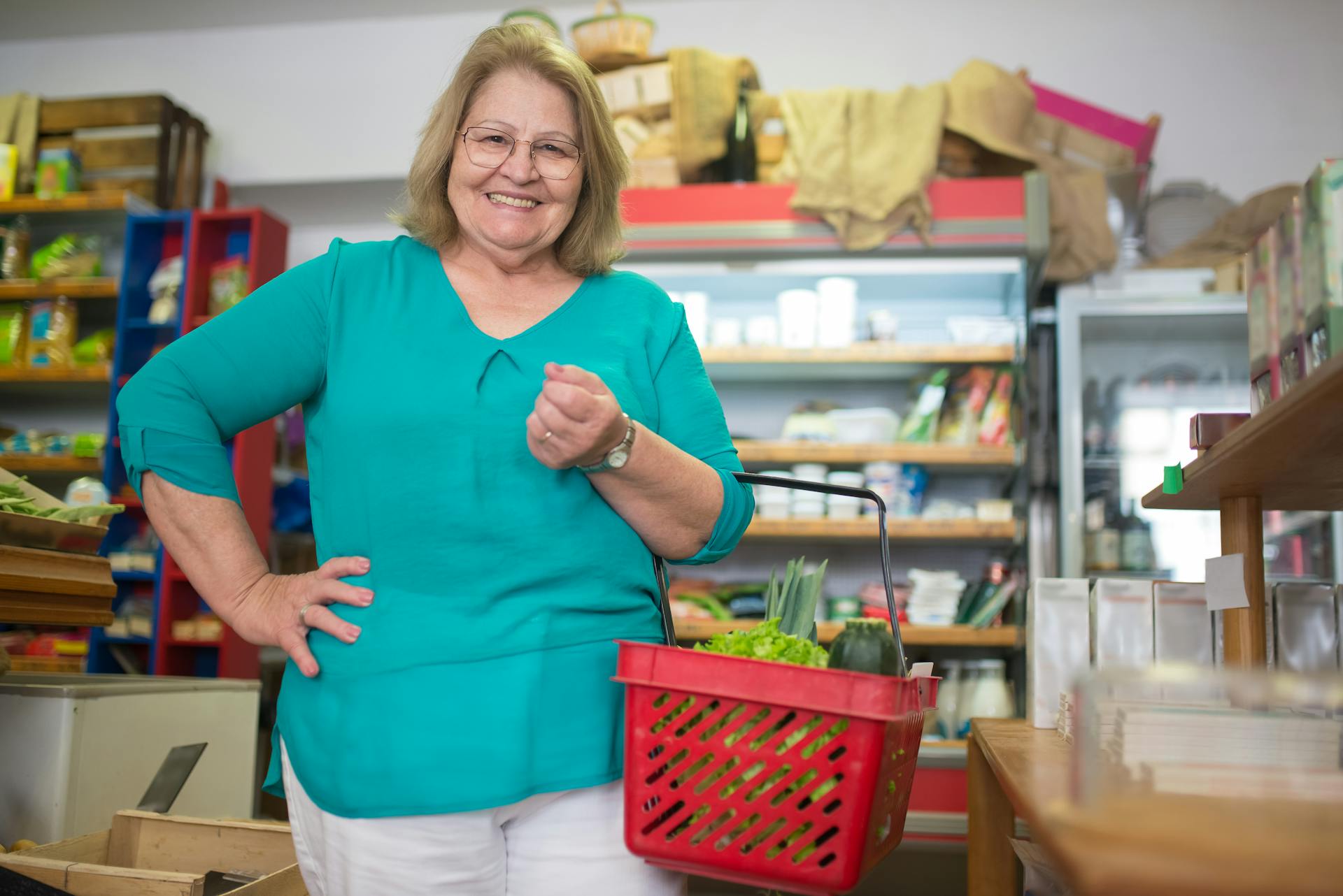 Una mujer sonriente con una cesta de la compra en una tienda | Fuente: Pexels