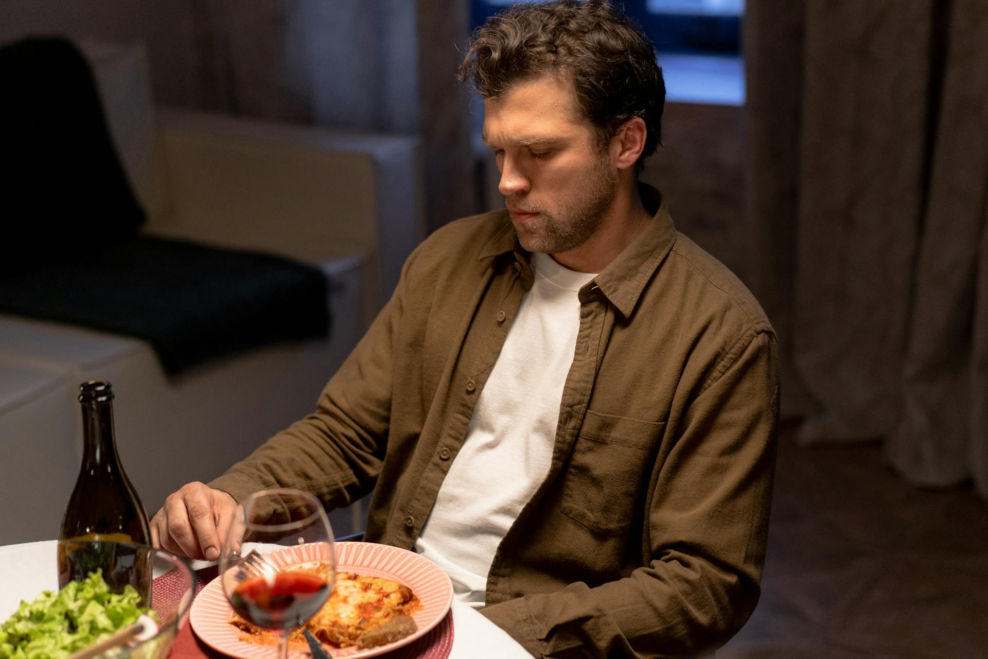 Un hombre pensativo mirando su plato de comida | Fuente: Pexels