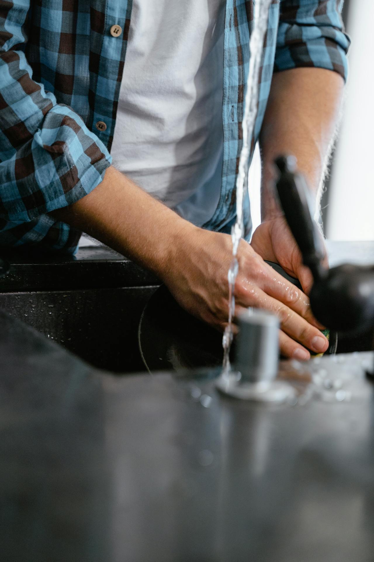 Recorte de un hombre lavando un plato | Fuente: Pexels