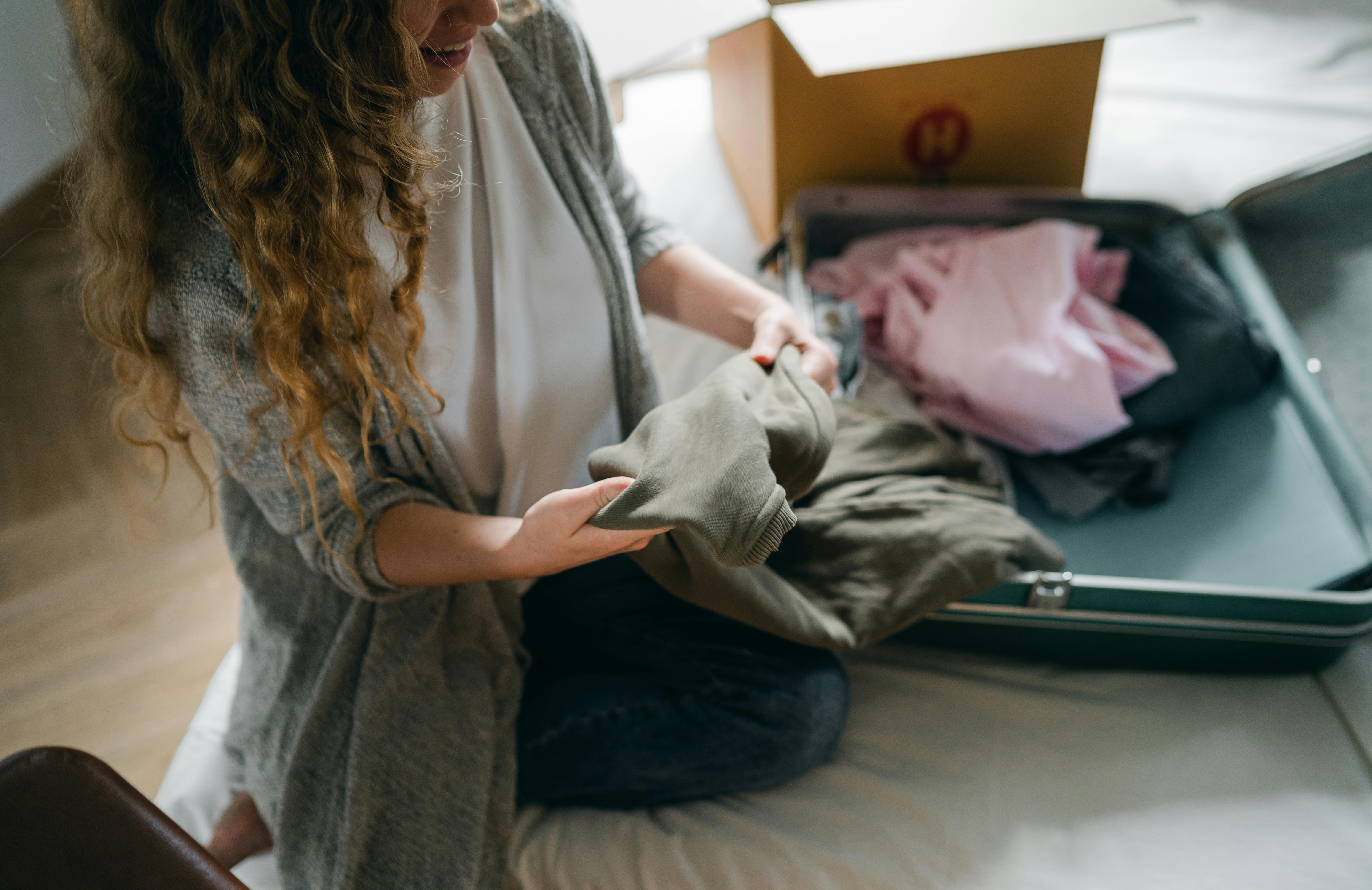 Una mujer guardando su ropa en una bolsa | Fuente: Pexels