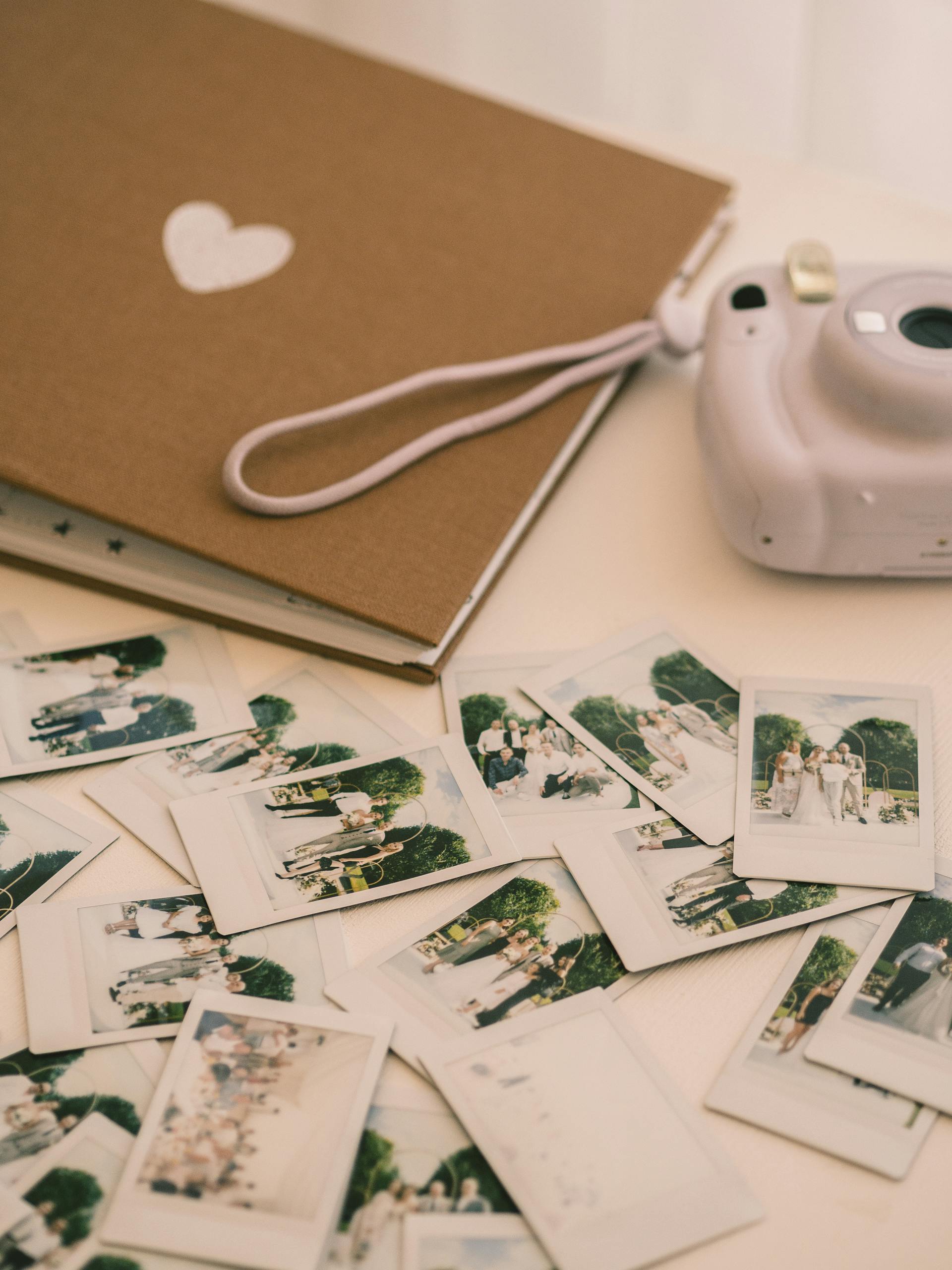 Una cámara, un álbum de fotos y fotografías sobre una superficie blanca | Fuente: Pexels