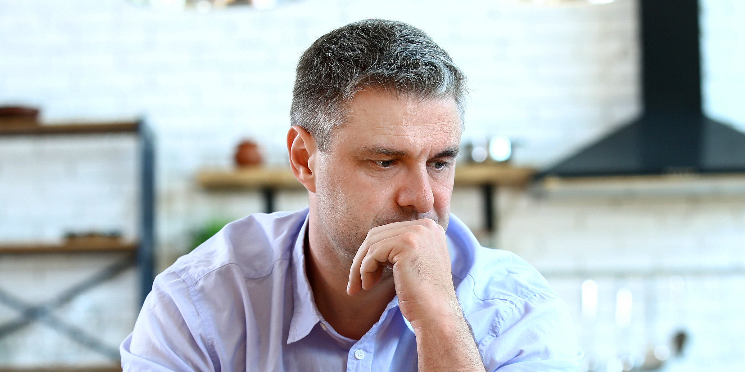Un hombre pensativo sentado en una mesa | Fuente: Shutterstock