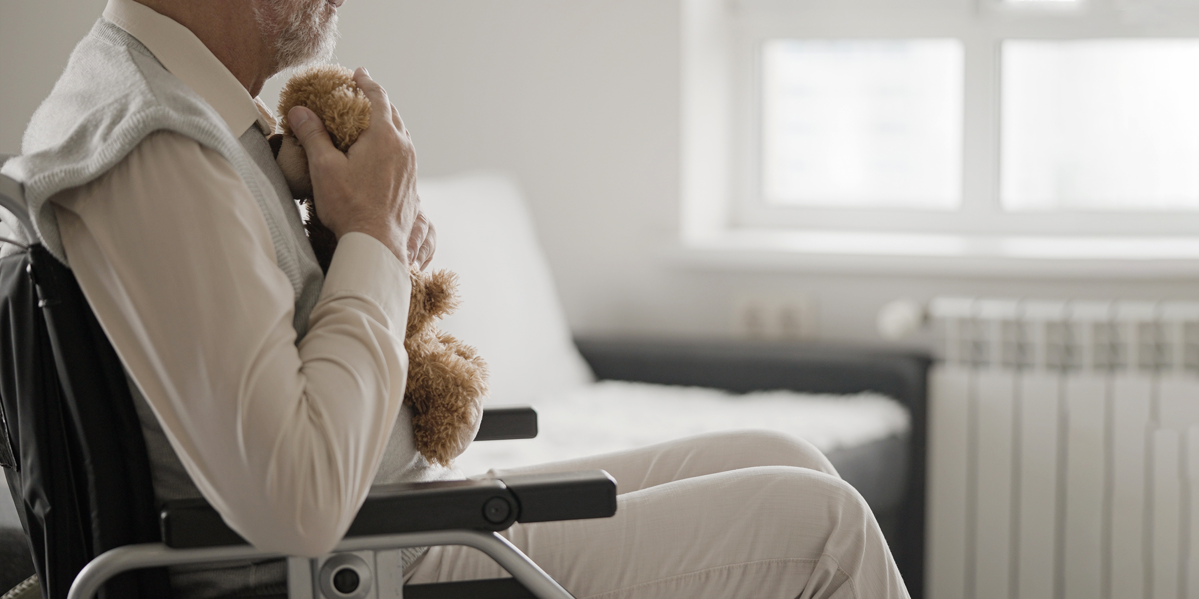 Anciano sentado en silla de ruedas con un oso de peluche | Fuente: Shutterstock