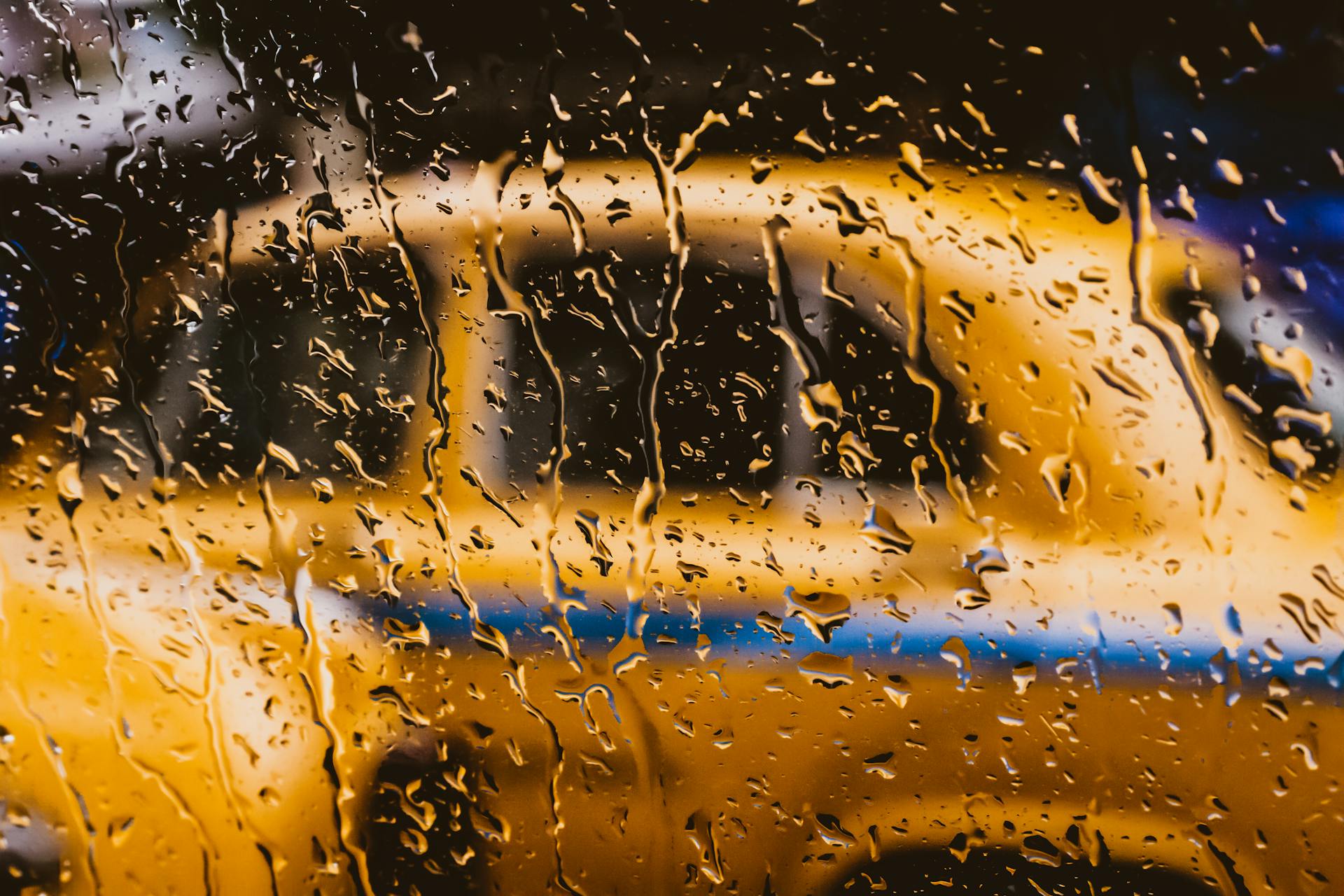 Una ventana mojada con un automóvil amarillo borroso detrás | Fuente: Pexels