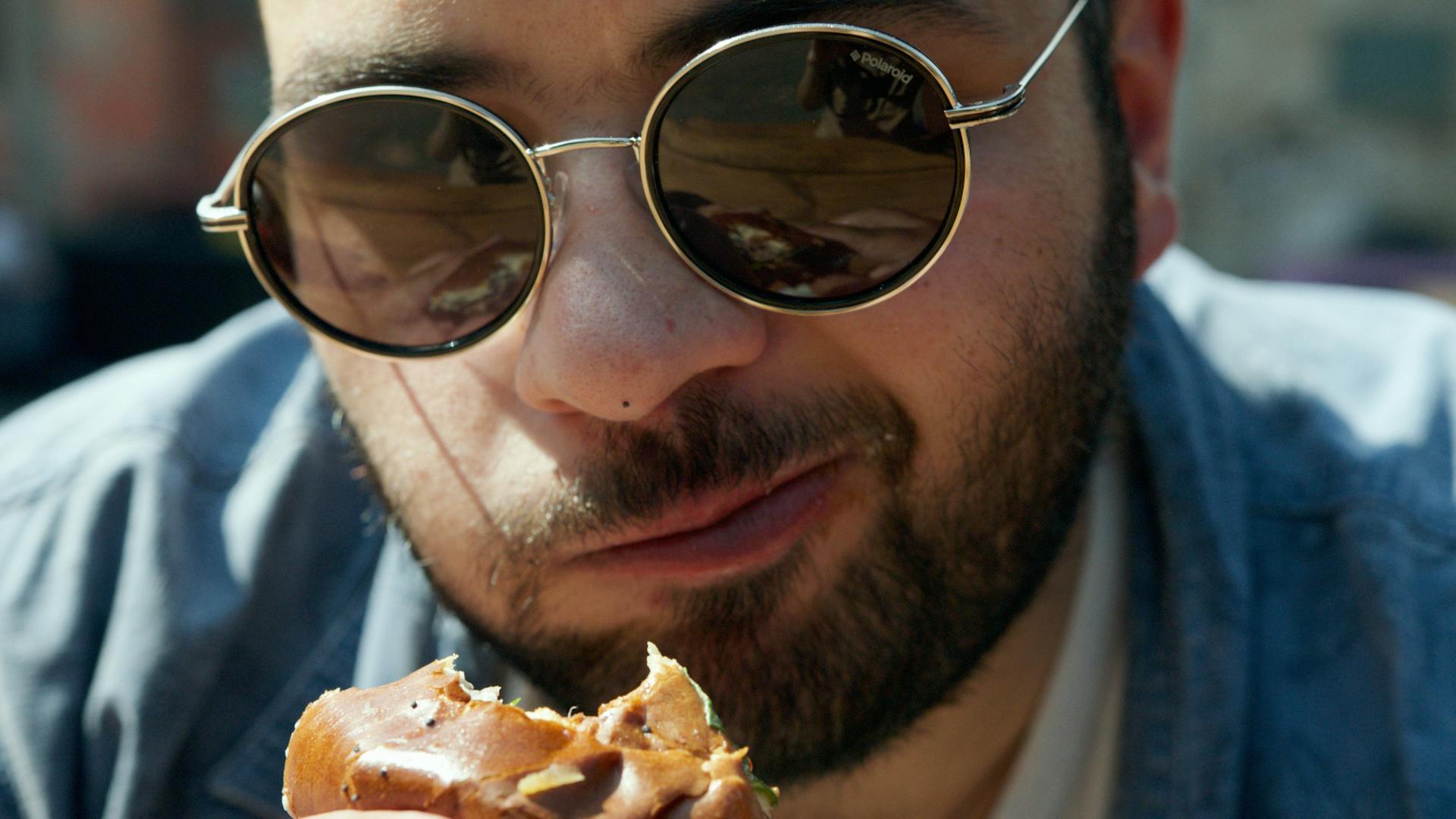 Un hombre con gafas de montura negra comiendo pizza | Fuente: Pexels