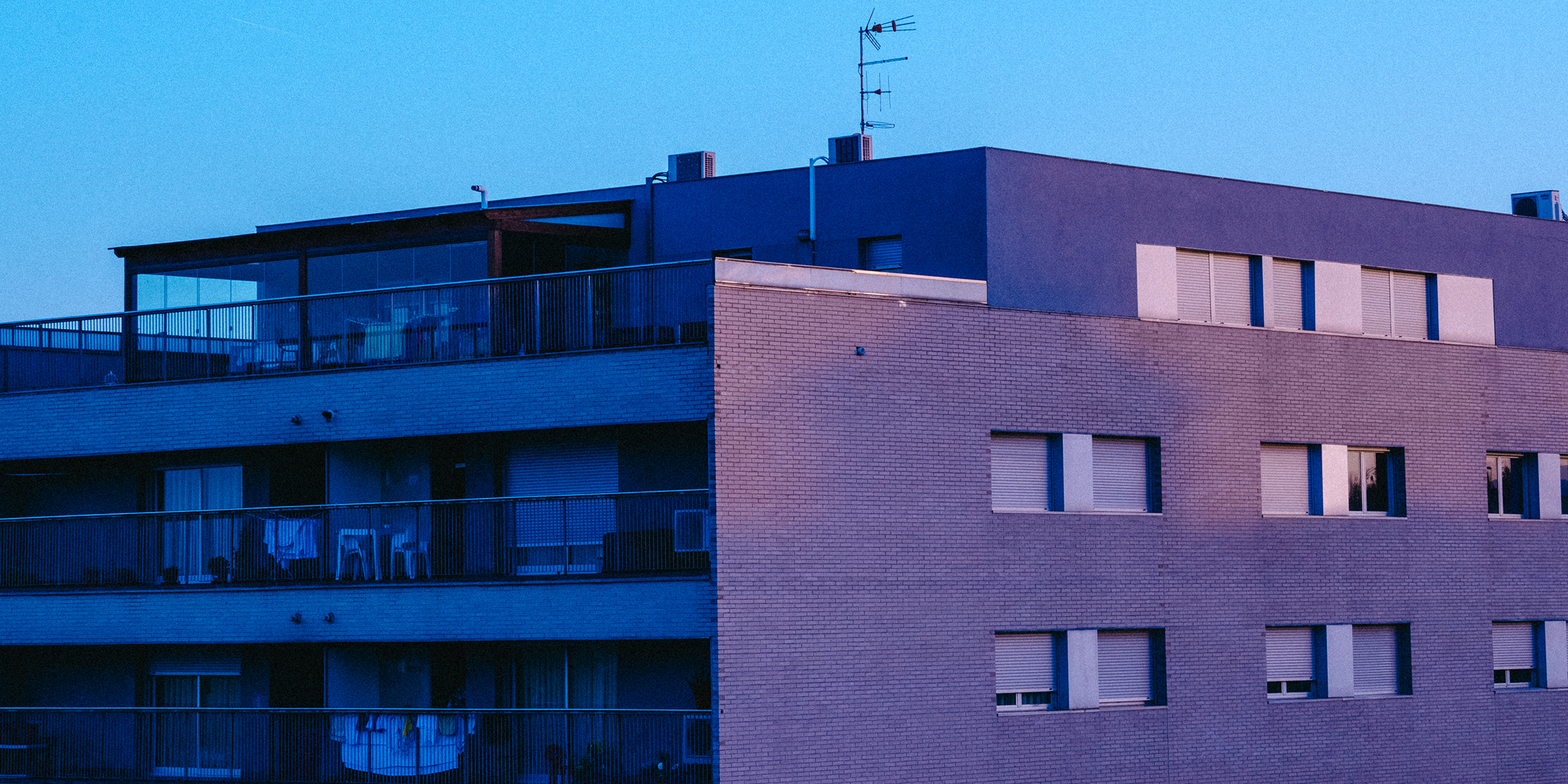 Un moderno edificio de apartamentos al atardecer | Fuente: Freepik / leyy