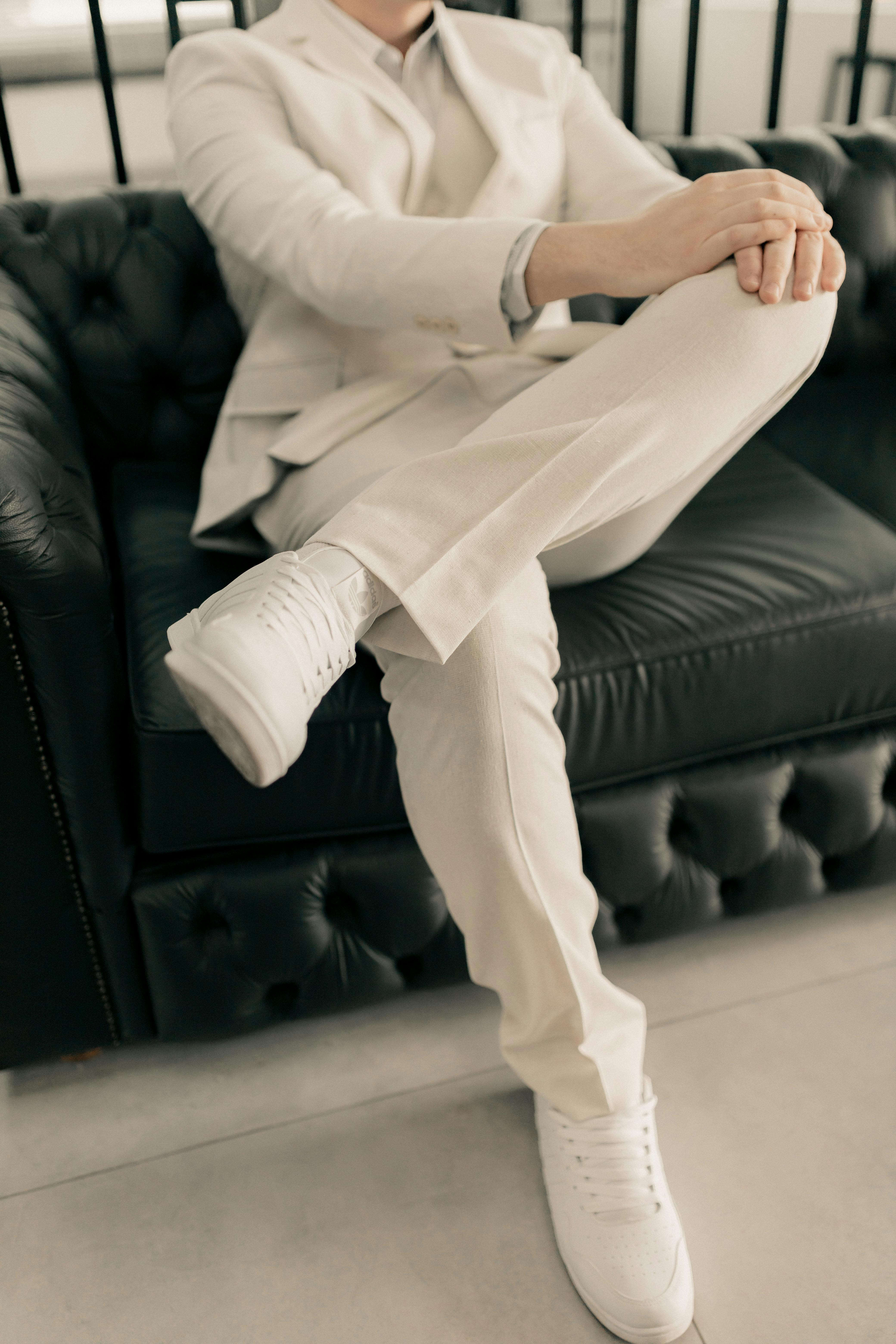 Persona con traje beige sentada en un sofá de cuero | Fuente: Pexels