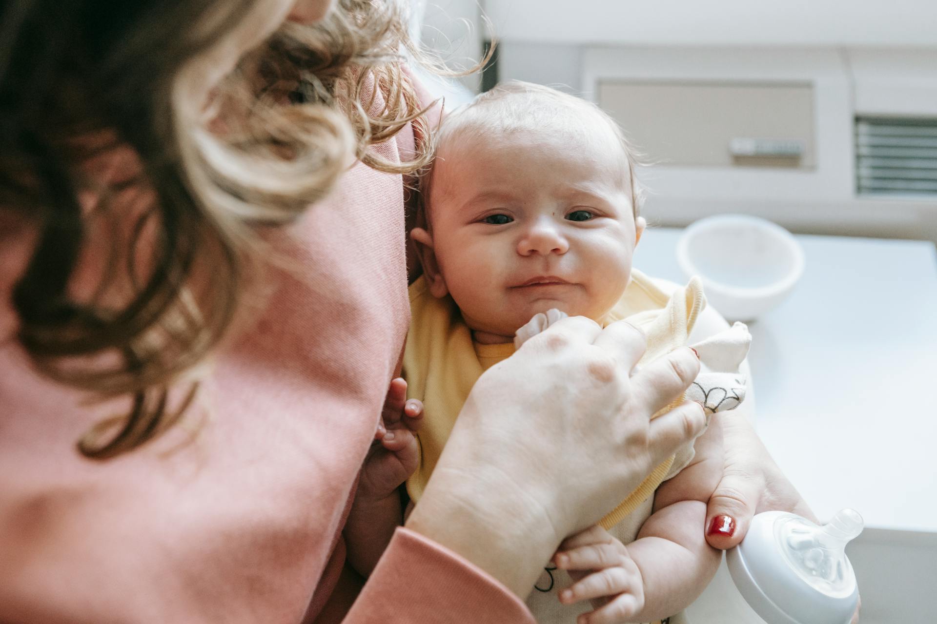 Una mujer con un bebé en brazos y un biberón | Fuente: Pexels