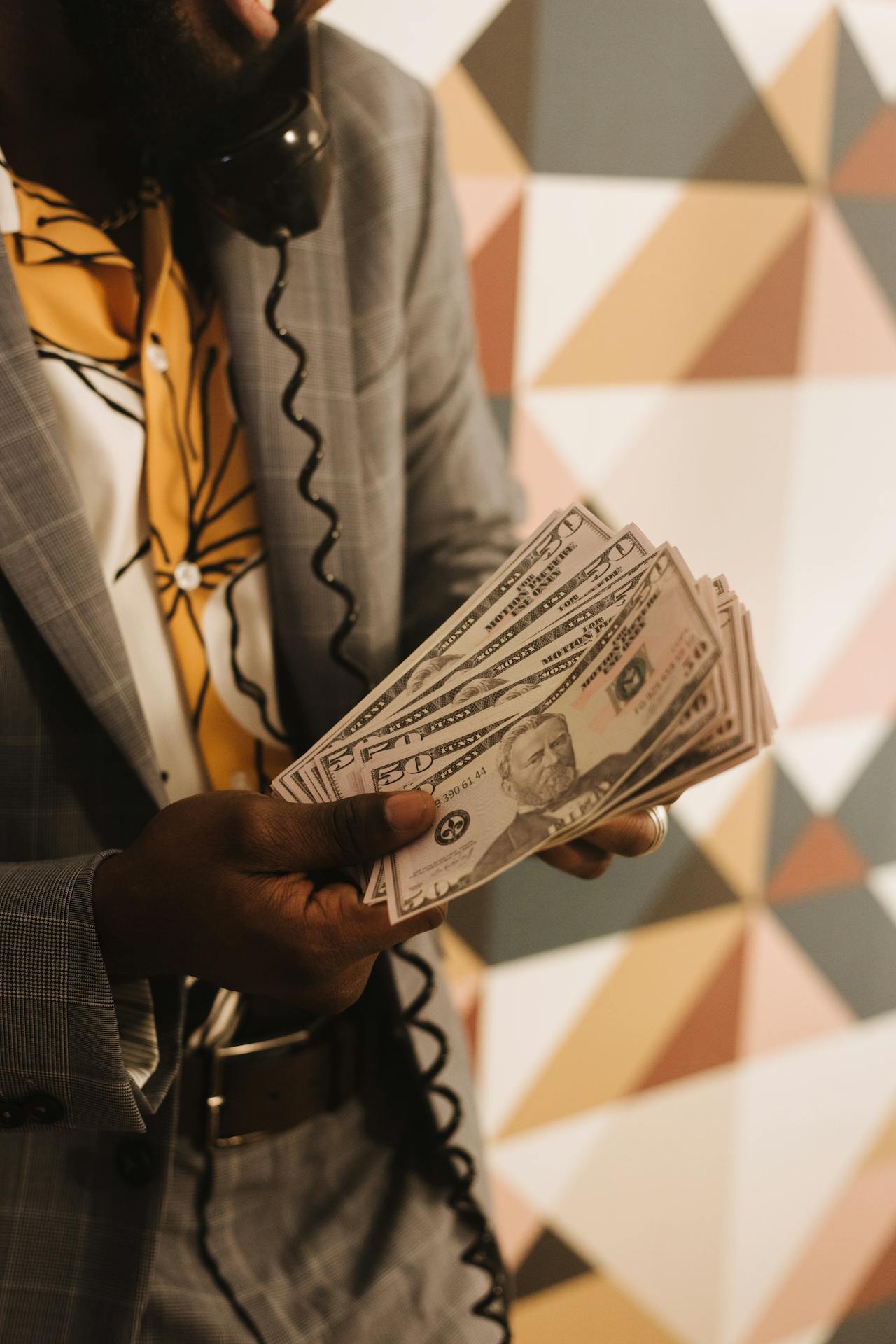Un hombre hablando por teléfono mientras sostiene dinero | Fuente: Pexels
