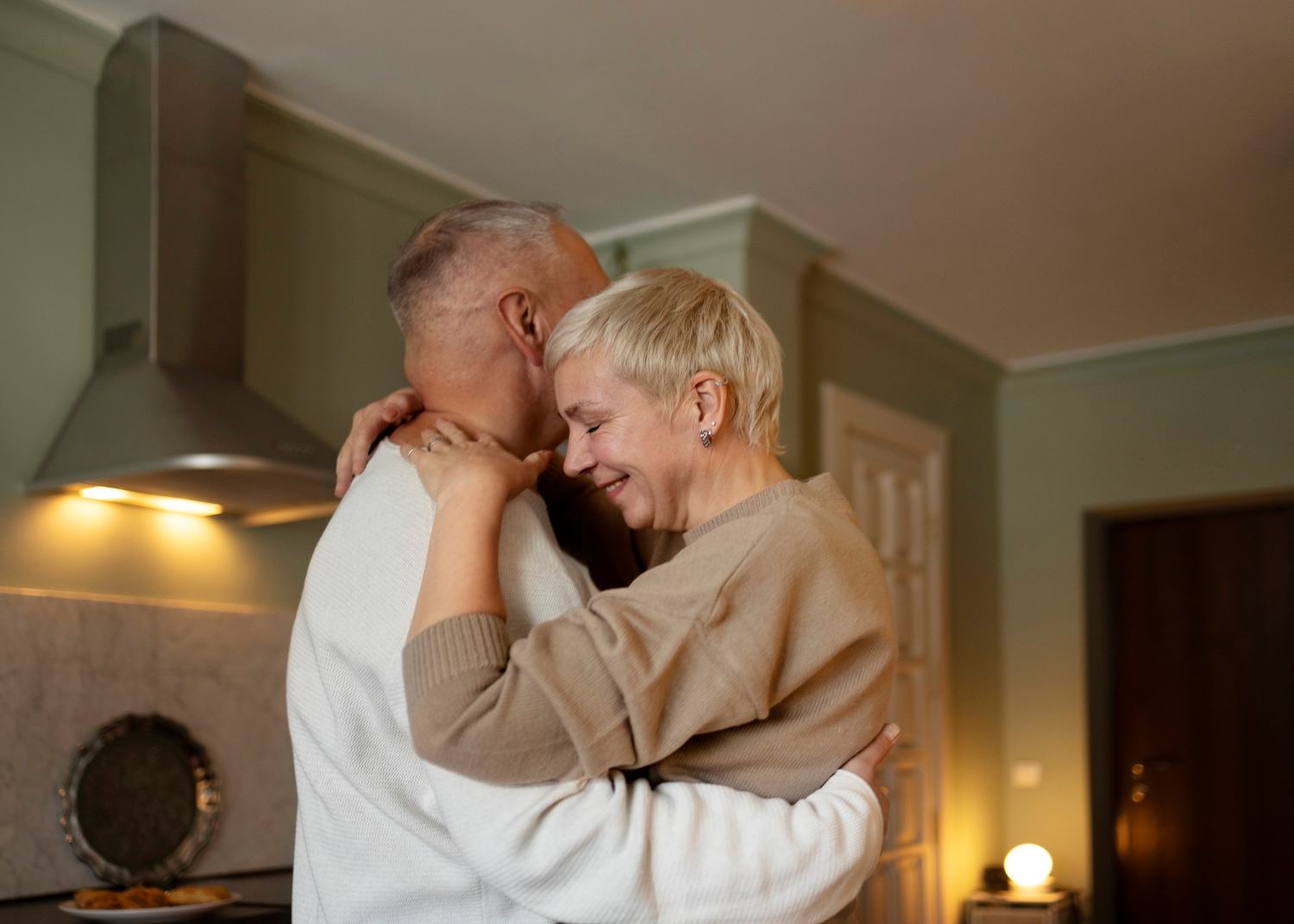Una pareja de ancianos abrazándose en la cocina | Fuente: Freepik