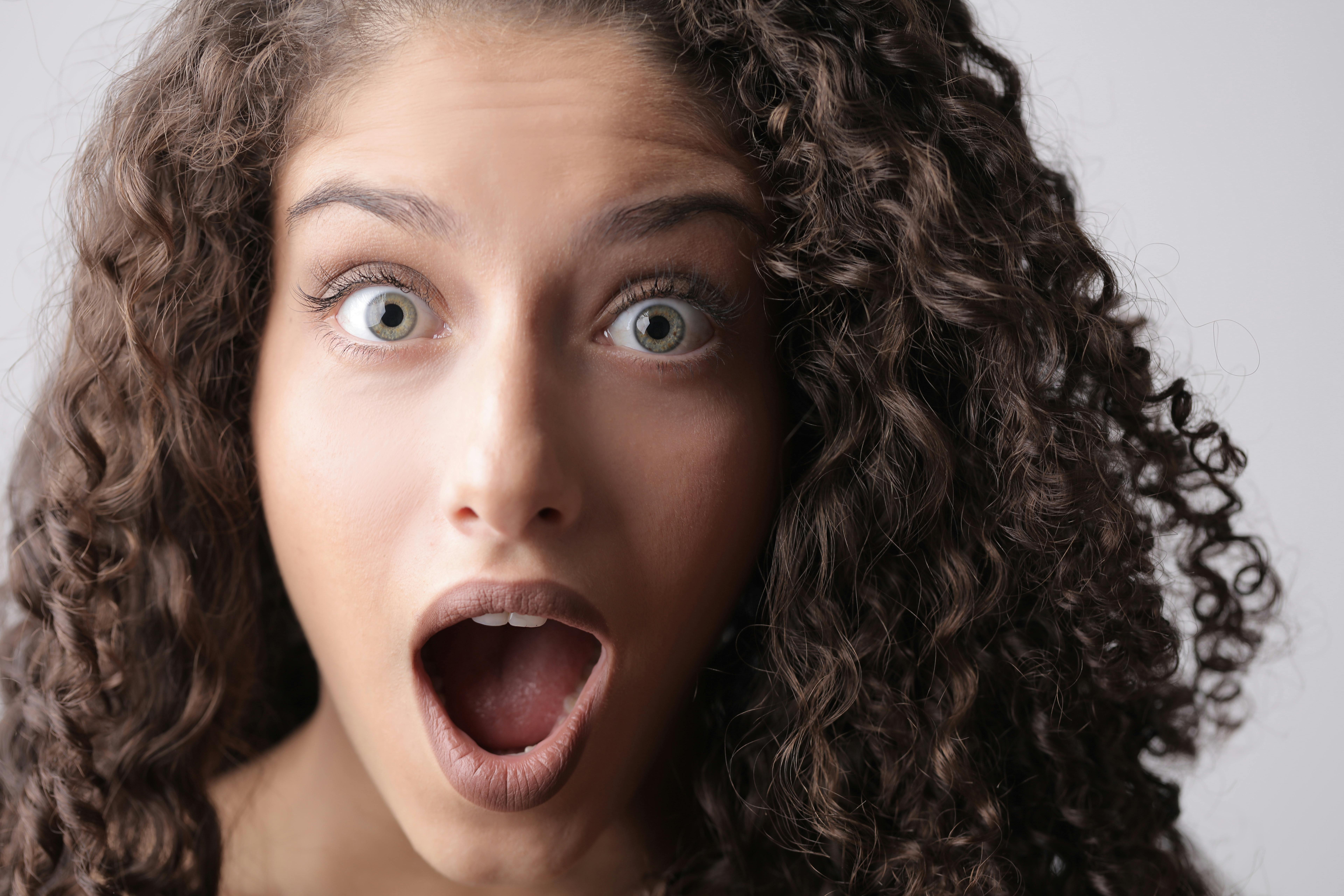 Una mujer sorprendida con el pelo rizado castaño | Fuente: Pexels