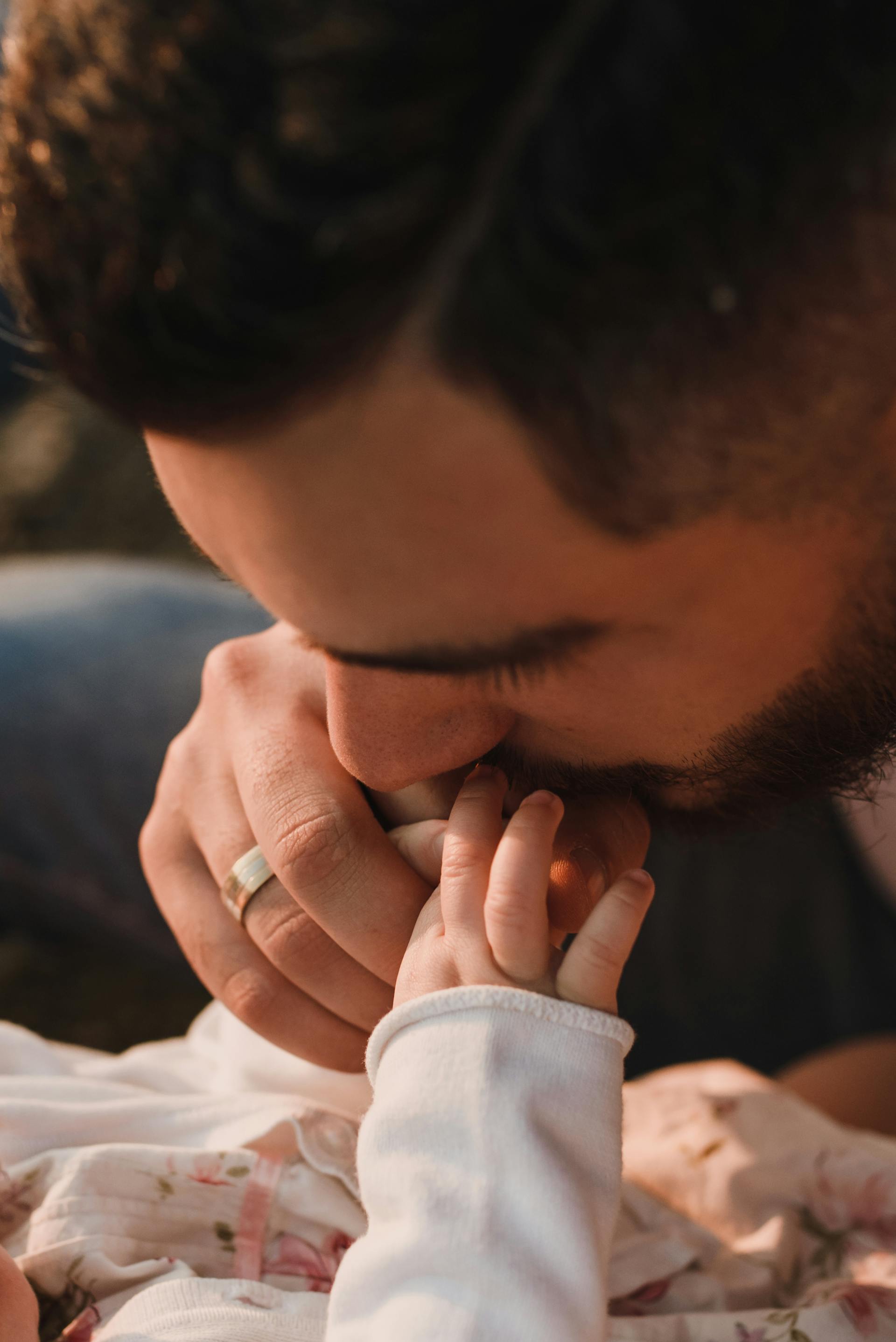 Primer plano de un padre besando la mano de su bebé | Fuente: Pexels