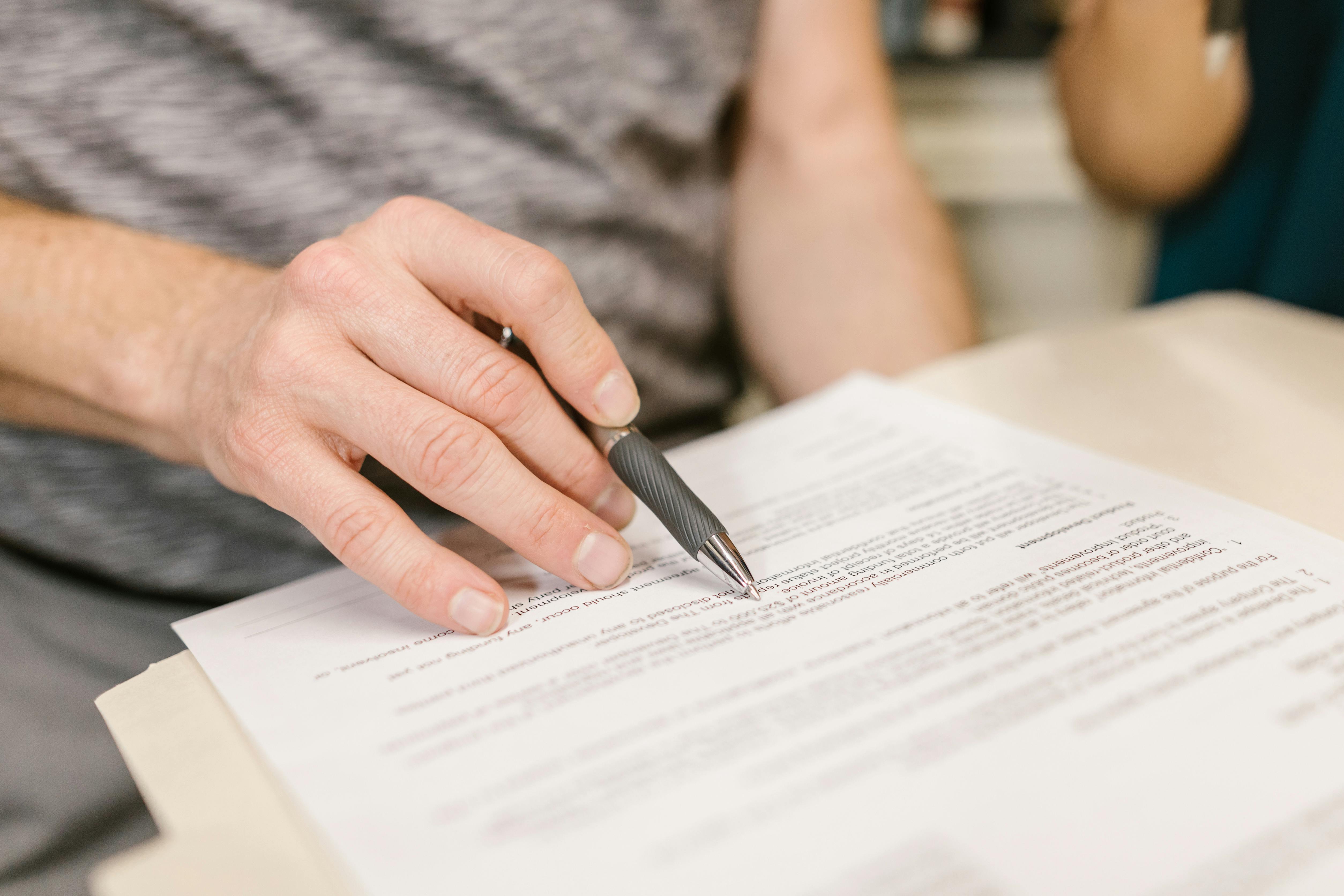 Una persona firmando documentos | Fuente: Pexels