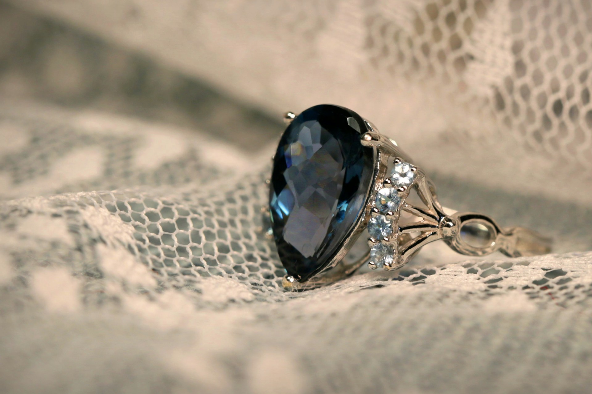 Un anillo tachonado de piedras sobre un paño de encaje blanco | Fuente: Unsplash