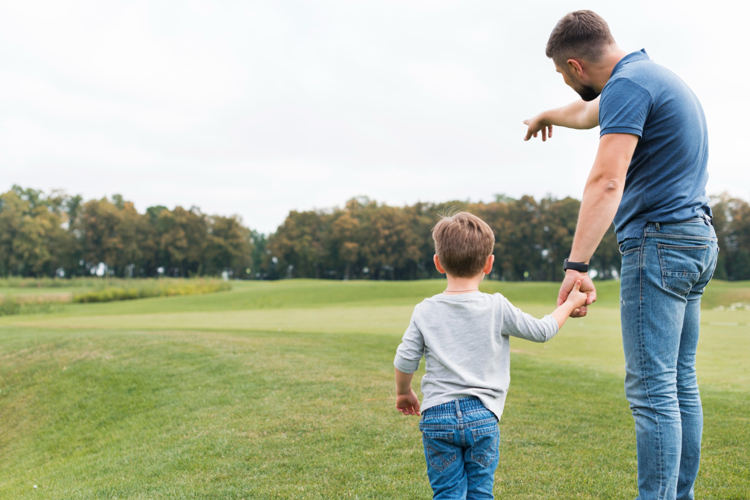 Un hombre cogido de la mano de un niño pequeño mientras exploran juntos la naturaleza | Fuente: Freepik
