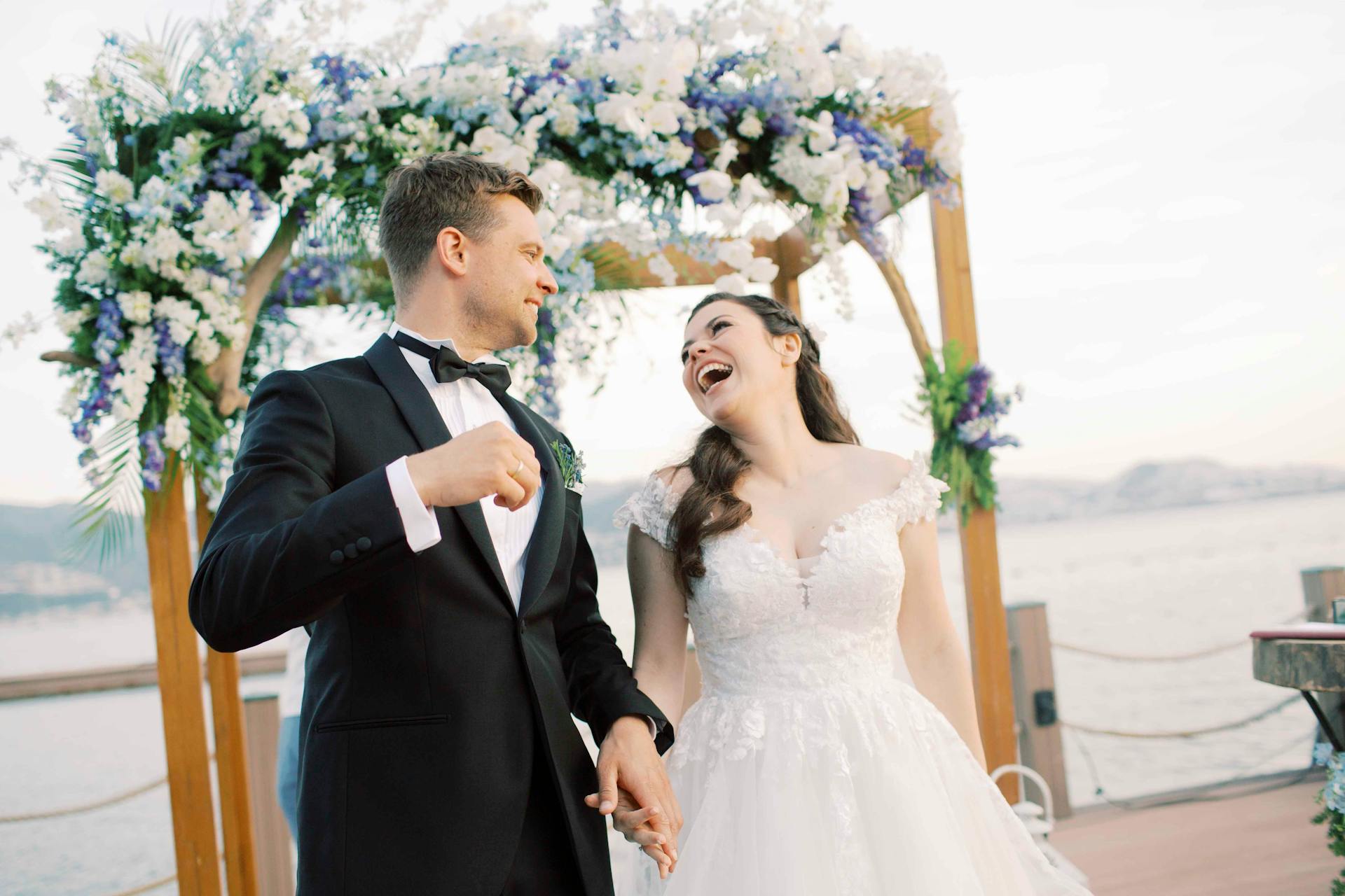 Una novia y un novio tomados de la mano y riendo | Fuente: Pexels