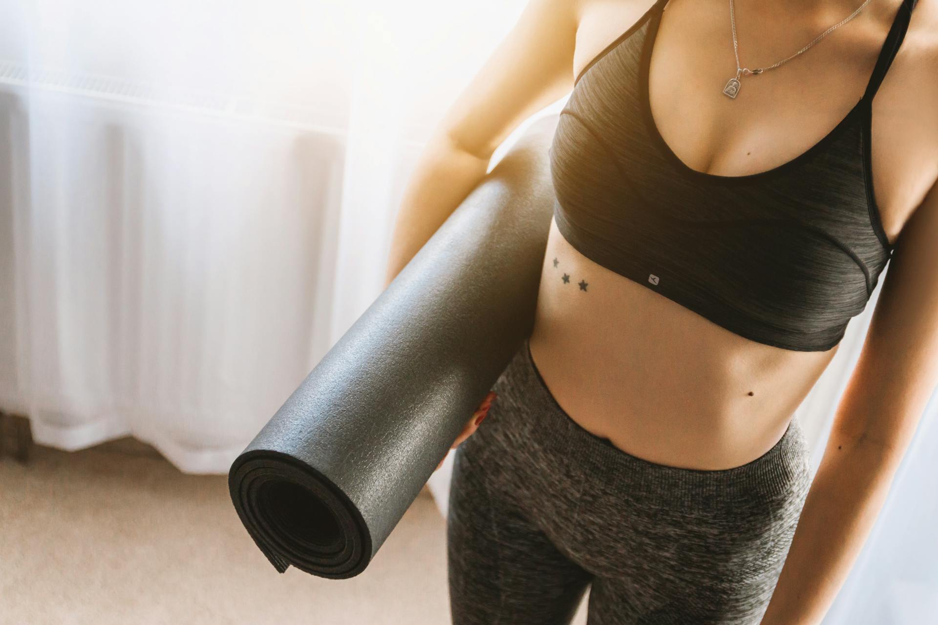 Una mujer sujetando una esterilla de yoga | Fuente: Pexels