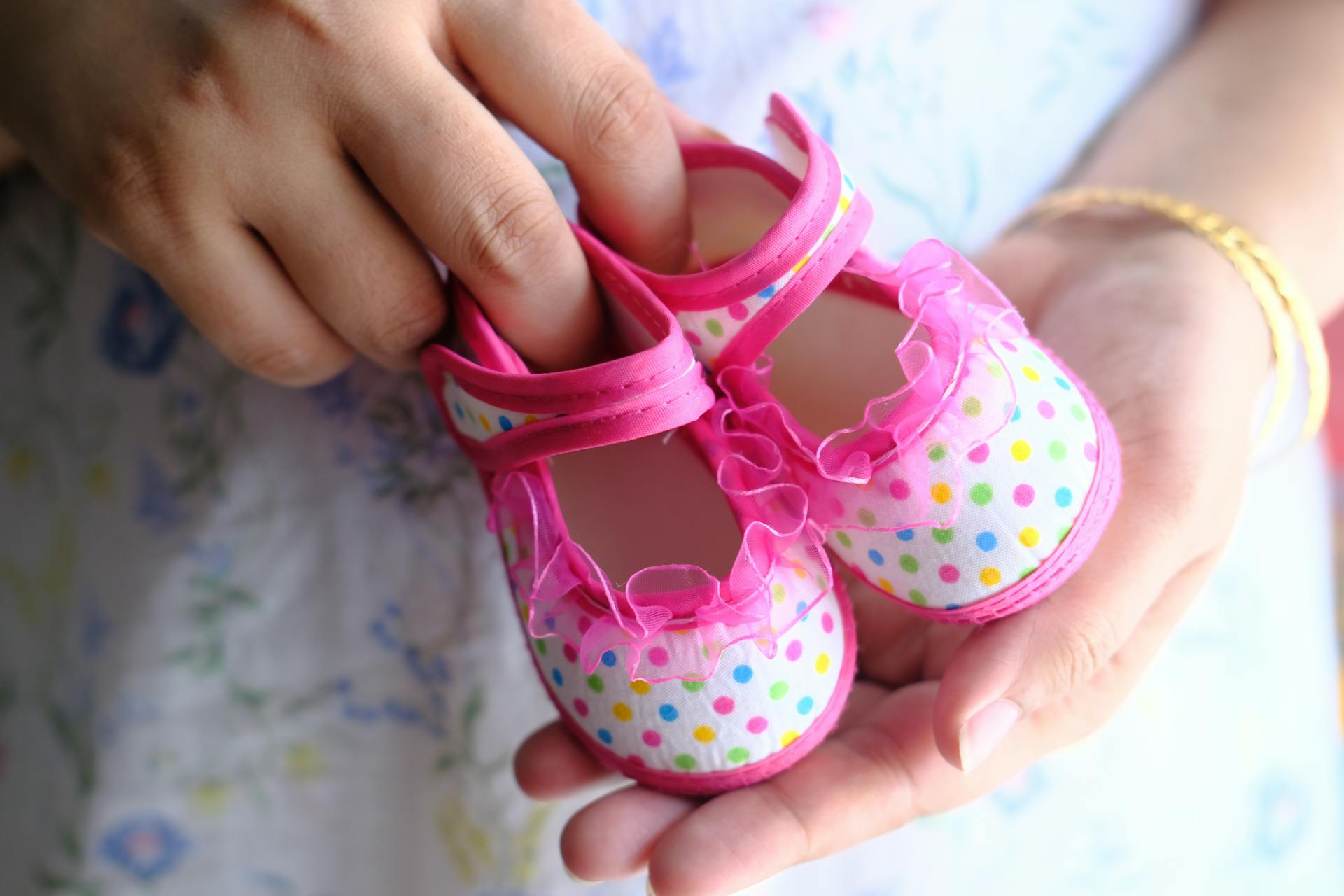 Una mujer con unos zapatitos rosas de bebé | Fuente: Pexels
