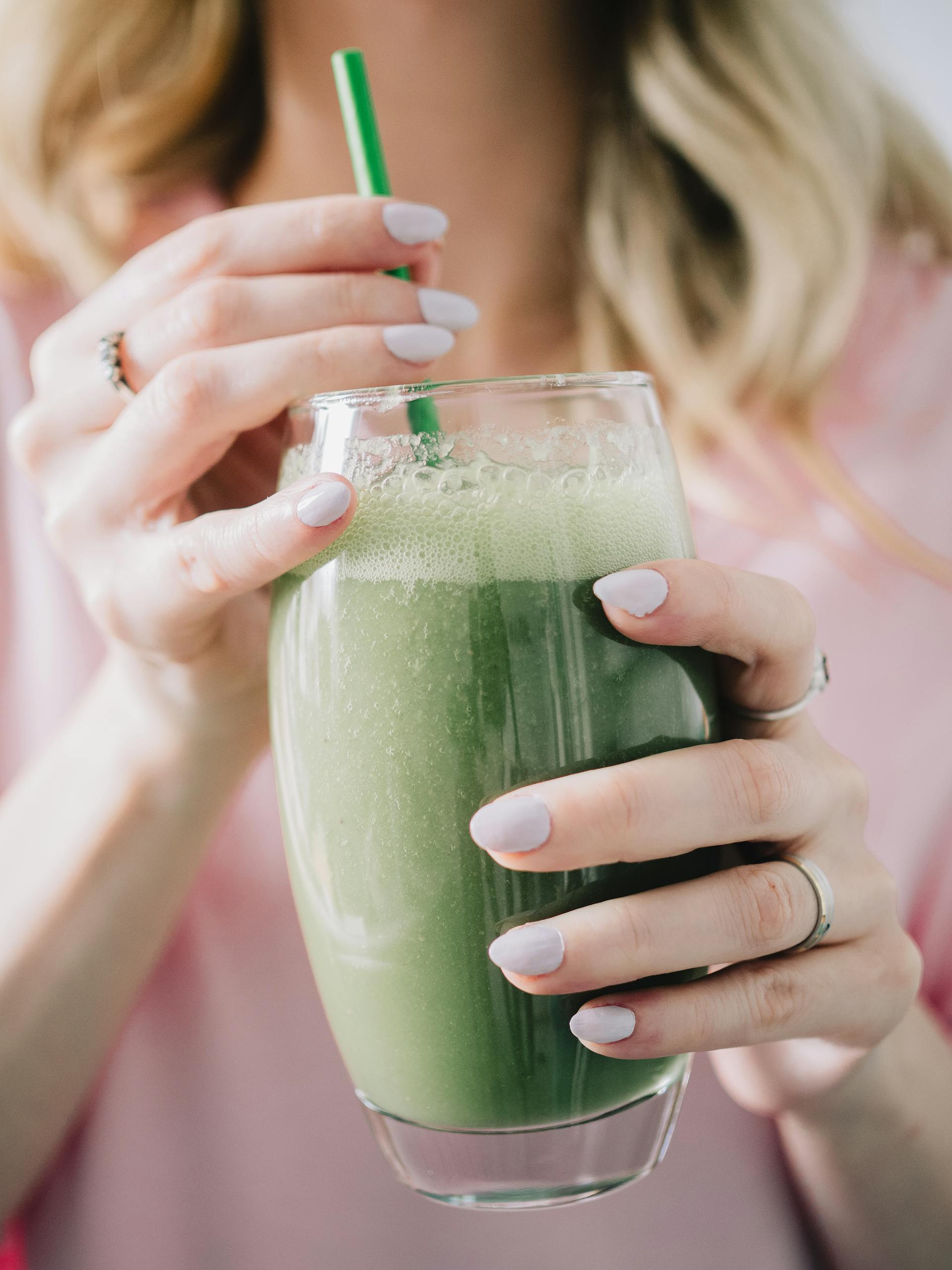 Una mujer con un vaso de batido verde en la mano | Fuente: Pexels
